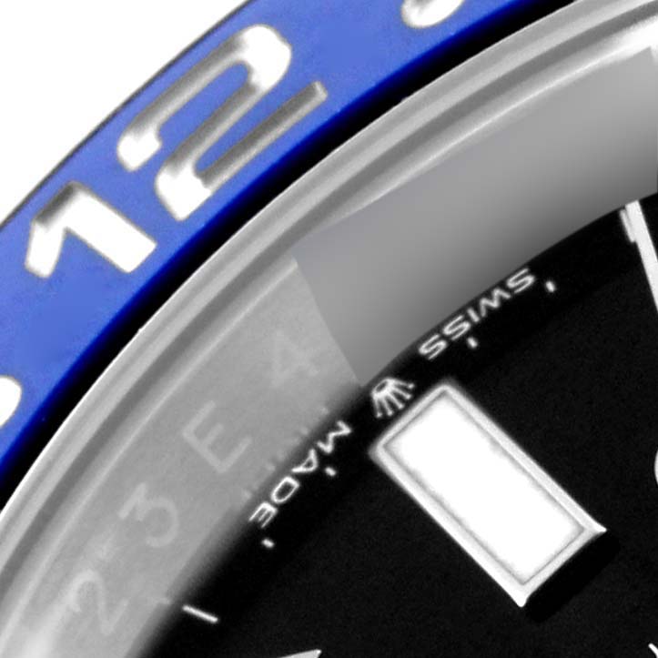 The image shows a close-up of the Rolex GMT-Master 126710 Men's Stainless Steel Black Dial 126710 Men's Stainless Steel Black Dial bezel with the number "12" and part of the dial with the "Swiss Made" text.