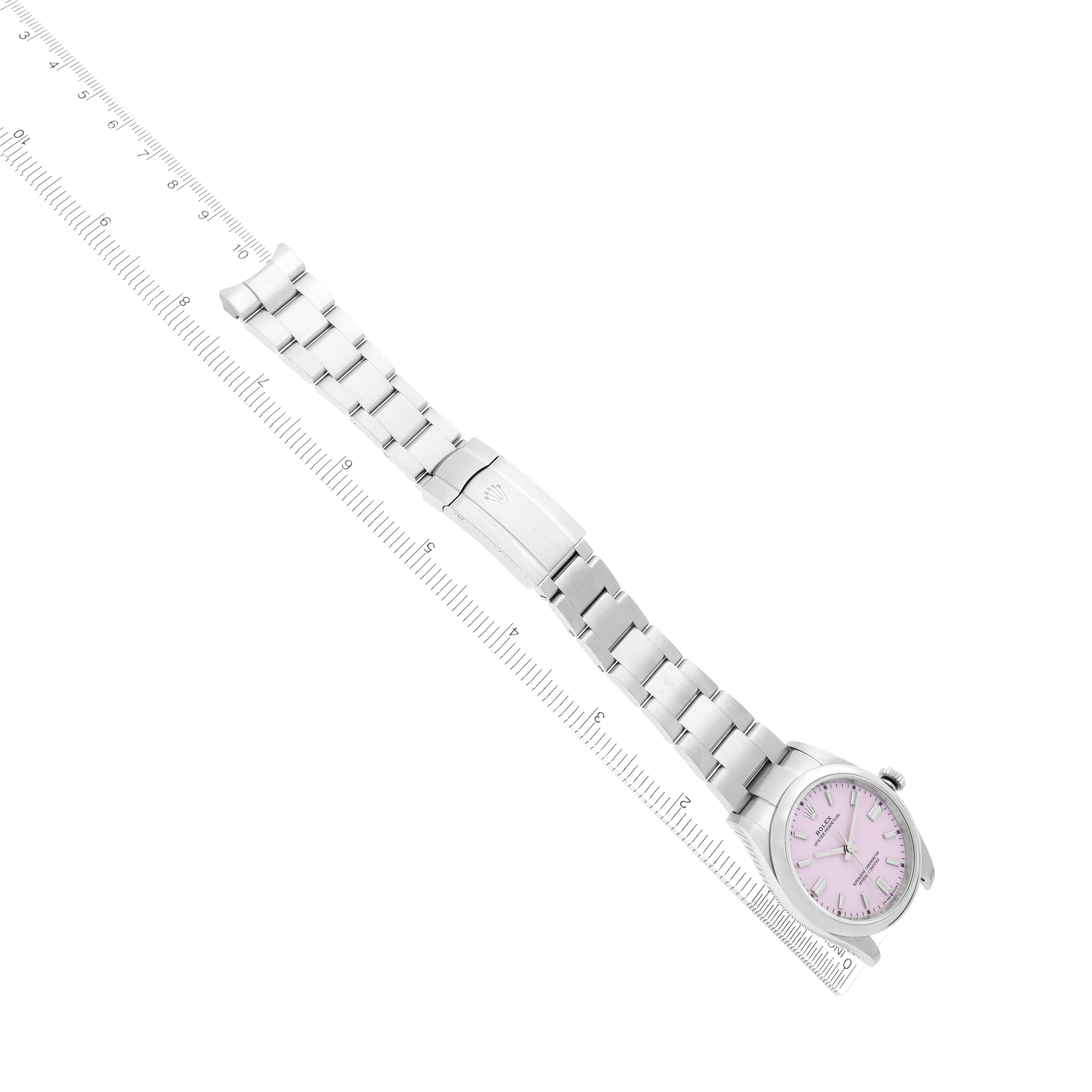 The Rolex Oyster Perpetual 126000 Men
s Stainless Steel Pink Dial watch is shown from an angled top view, highlighting its bracelet and clasp alongside a ruler.