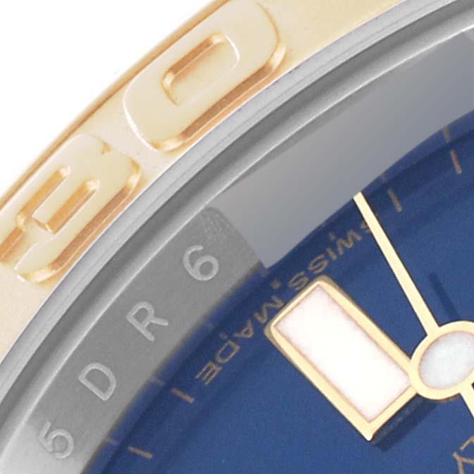 This close-up image of a Rolex Yacht-Master 16623 Men's Steel and Gold (two tone) Blue Dial 16623 Men's Steel and Gold (two tone) Blue Dial watch shows part of the bezel, minute hand, and dial with the "Swiss Made" label.