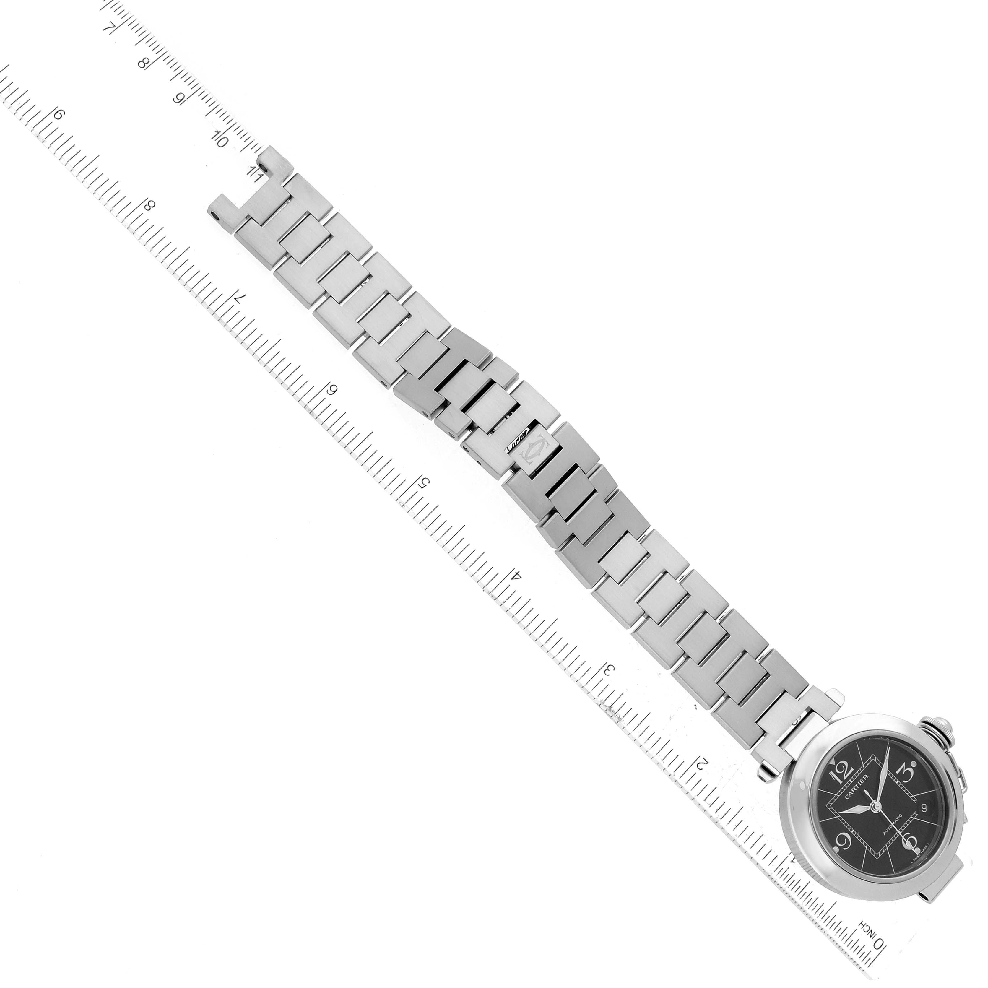 The image shows a top-down view of a Cartier Pasha W31076M7 Women's Stainless Steel Black Dial W31076M7 Women's Stainless Steel Black Dial watch, emphasizing the bracelet and face with a measuring ruler alongside.