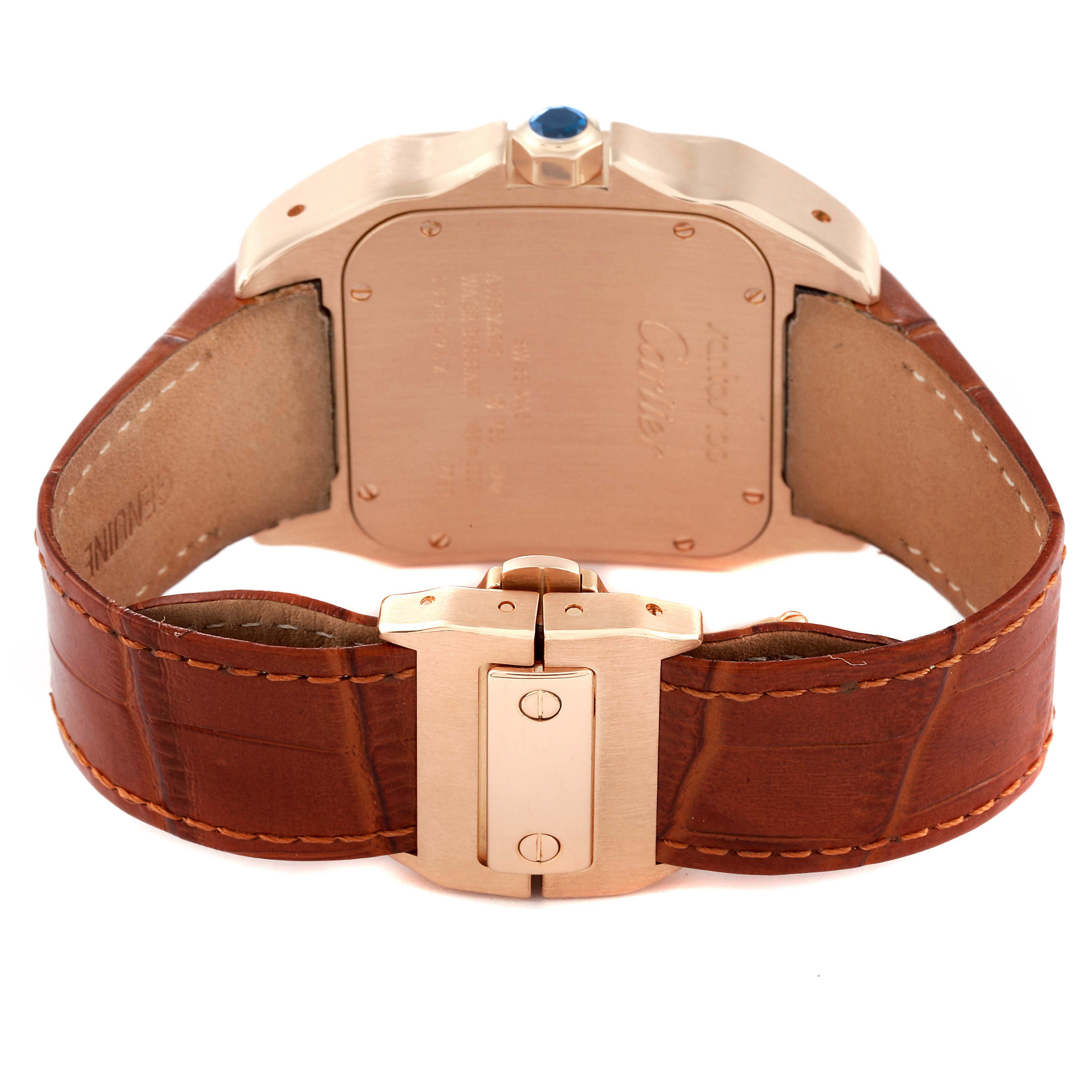 The image shows the back case and clasp of a Santos model watch by Cartier, featuring a brown leather strap and gold detailing.