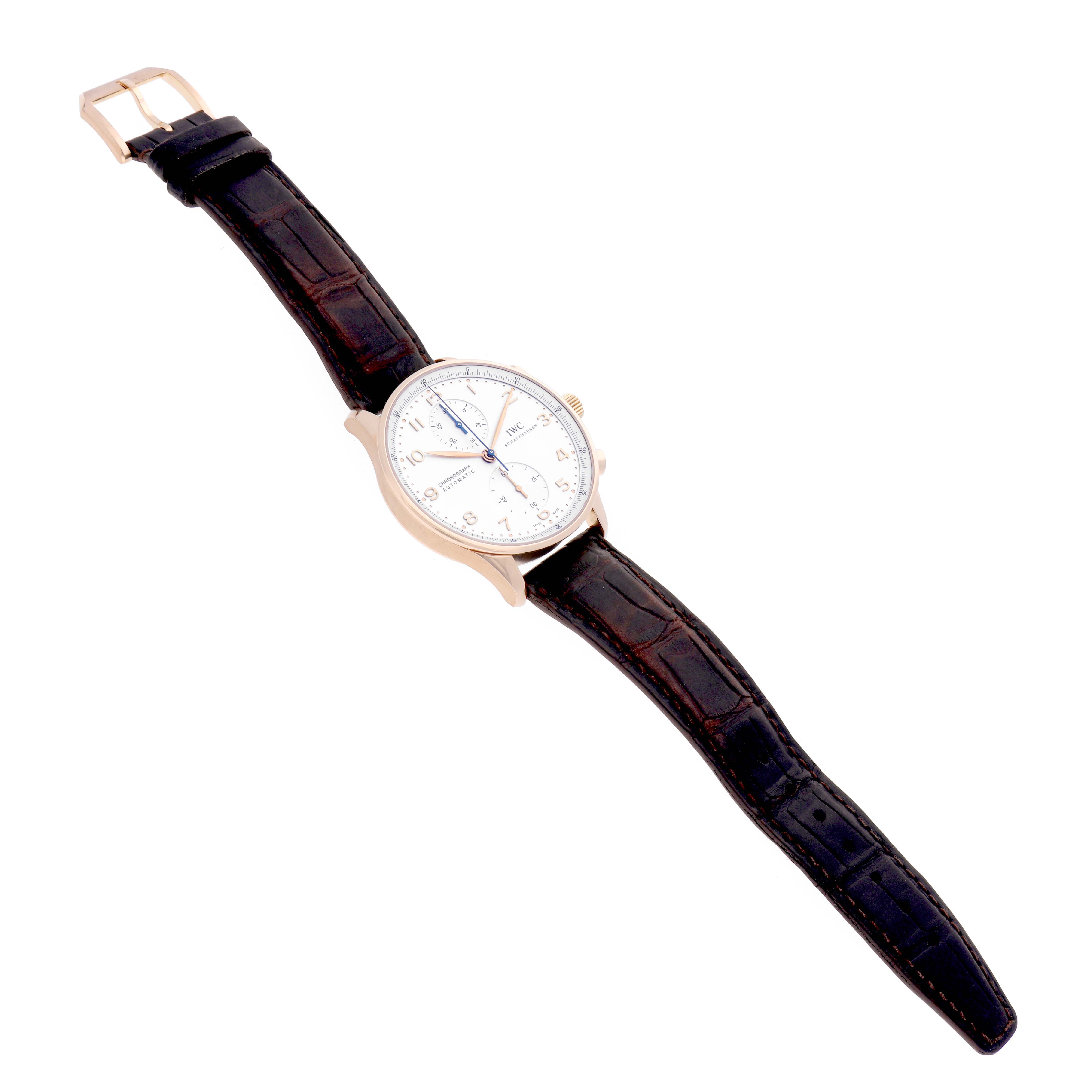 The IWC Portuguese IW371402 Men's Rose Gold Silver Dial IW371402 Men's Rose Gold Silver Dial model watch is shown at a slight angled view, displaying its face, bezel, crown, and leather strap.