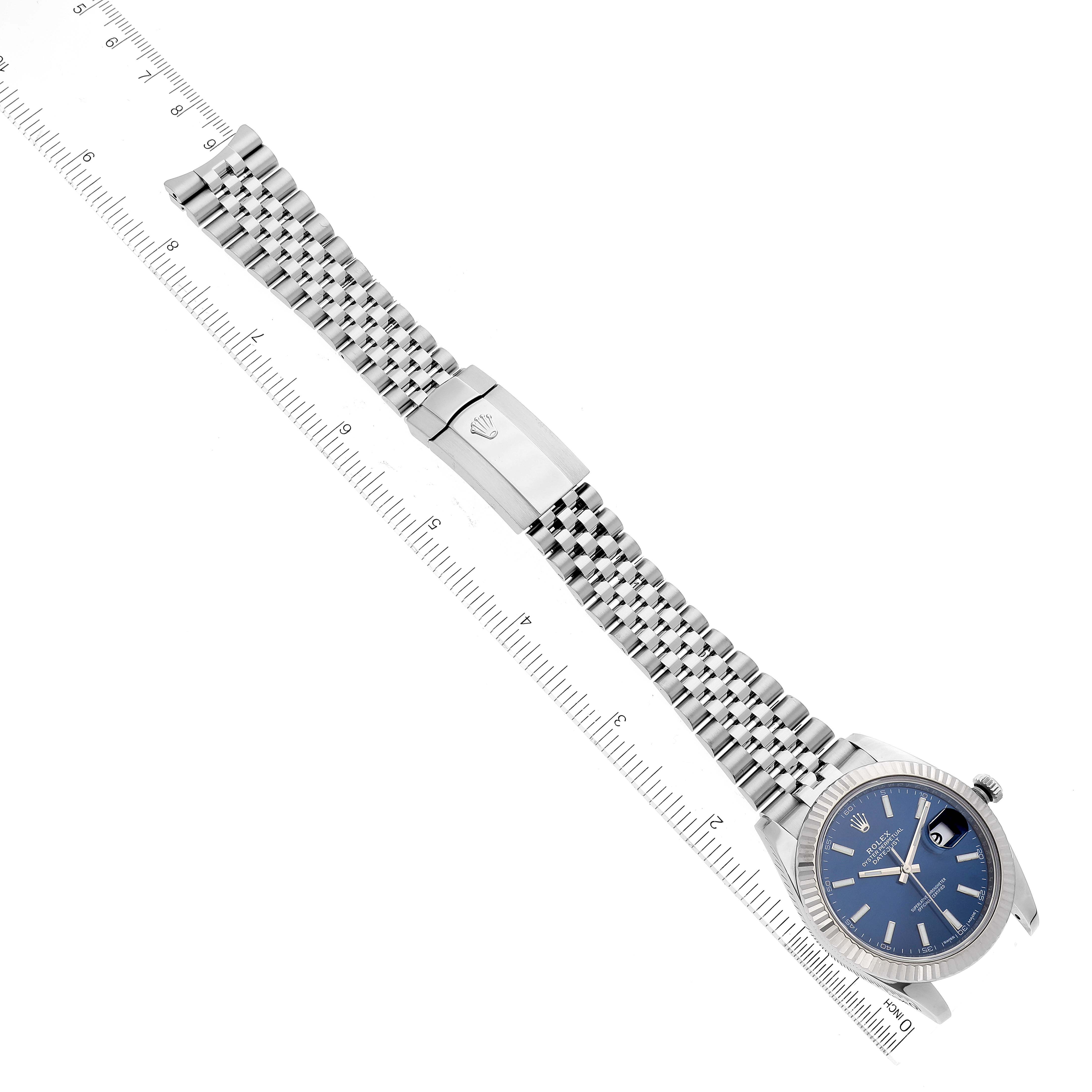 The image shows a top-down view of a Rolex Datejust 41 126334 Men's Stainless Steel Blue Dial 126334 Men's Stainless Steel Blue Dial watch, displaying the face, bracelet, and clasp with a measuring scale.