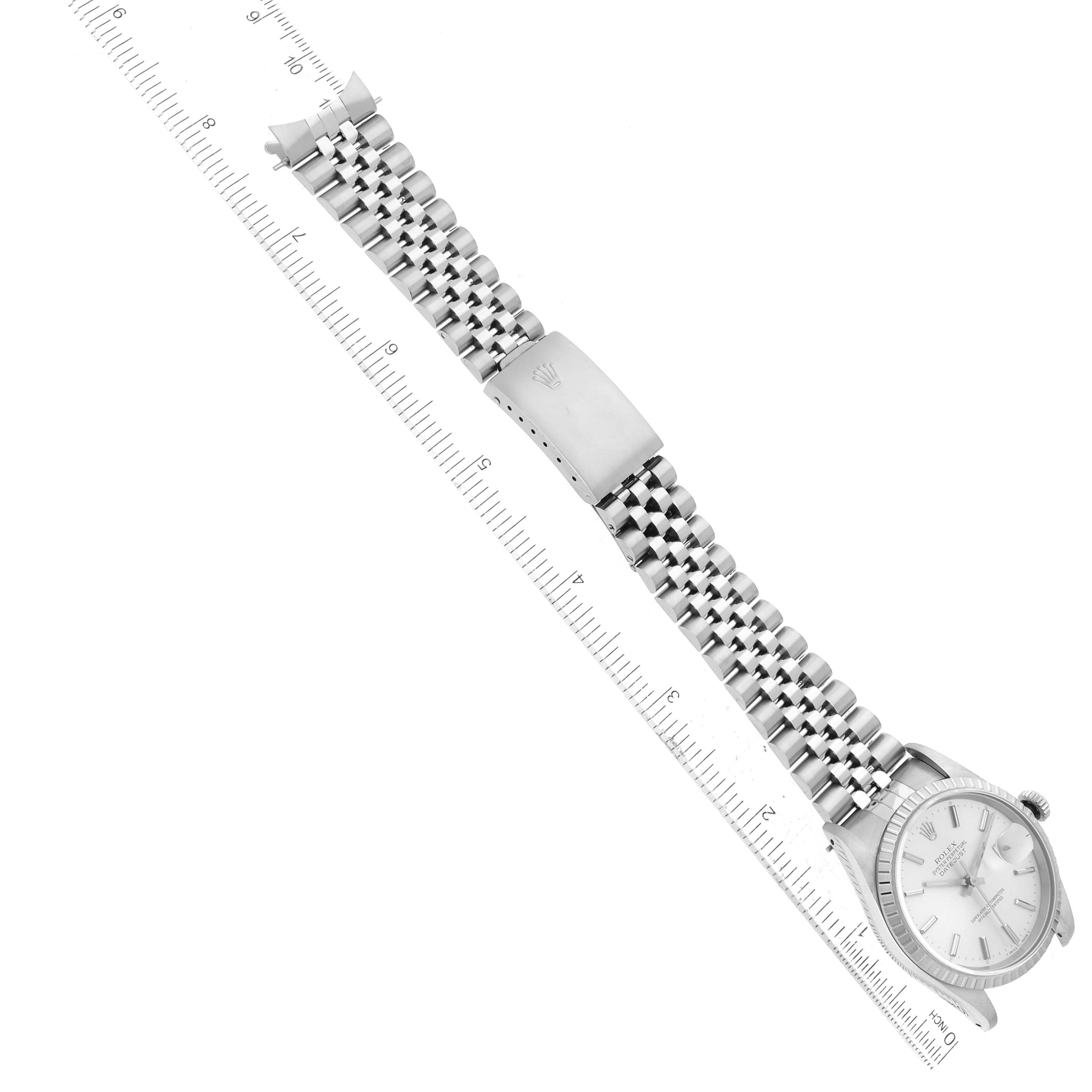 The image shows a top-down view of a Rolex Datejust 16220 Men's Stainless Steel Silver Dial 16220 Men's Stainless Steel Silver Dial watch with a stainless steel Jubilee bracelet, adjacent to a ruler for scale.