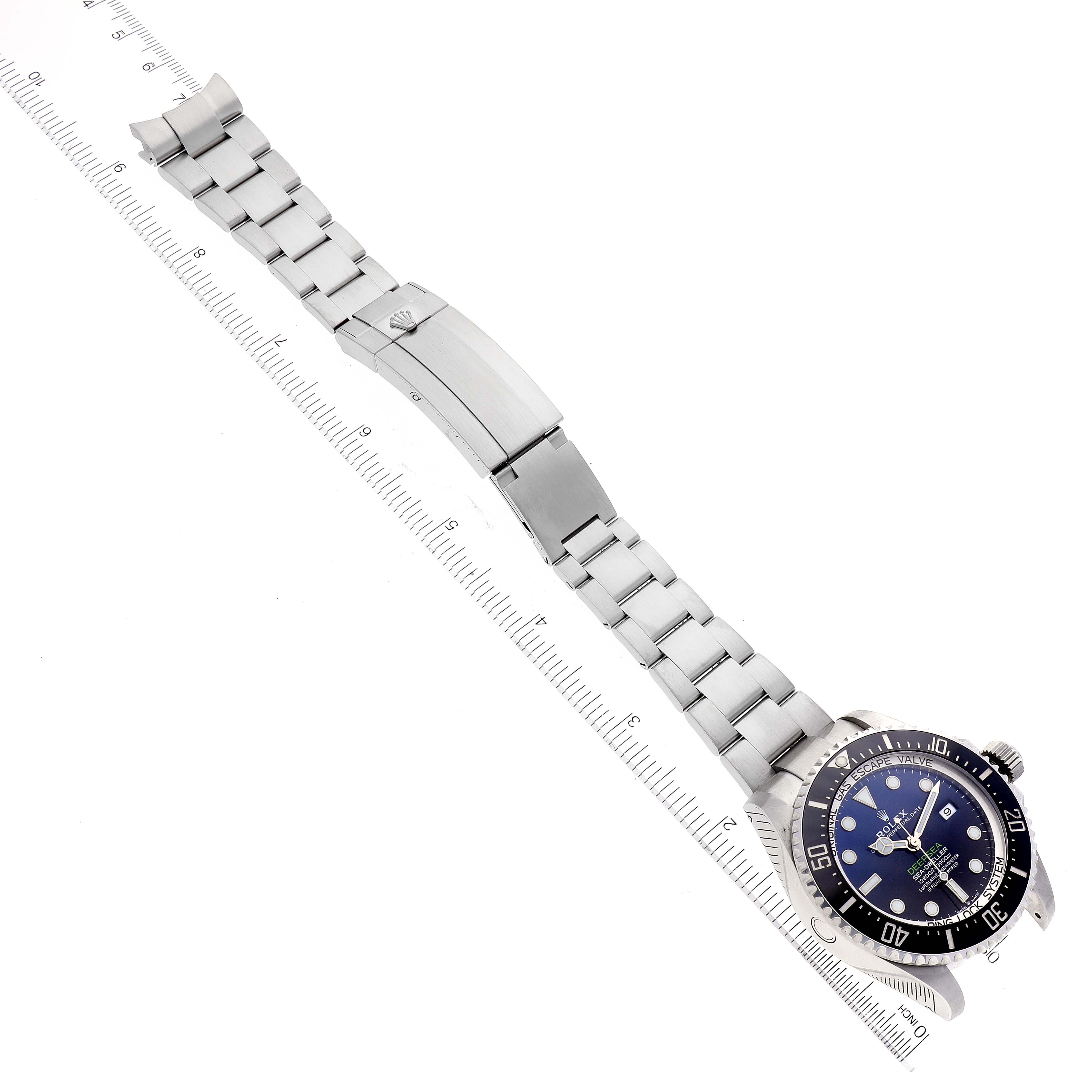 This image shows a top-down view of the Rolex Sea-Dweller 126660 Men's Stainless Steel Blue Dial 126660 Men's Stainless Steel Blue Dial watch, displaying its bezel, face, bracelet, and clasp alongside a ruler.