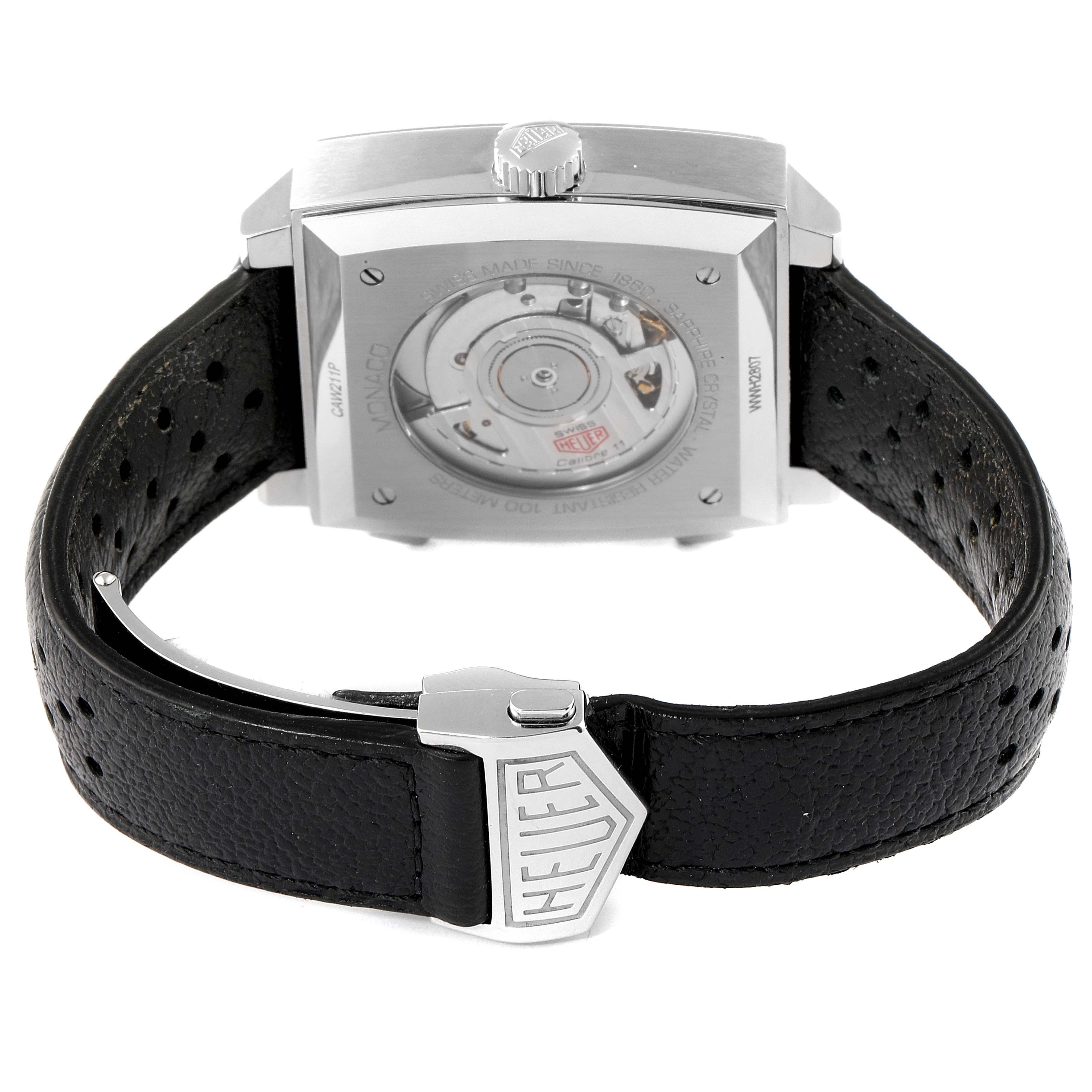 The image shows the back view of a Tag Heuer Monaco CAW211P Men's Stainless Steel Blue Dial CAW211P Men's Stainless Steel Blue Dial watch, highlighting the movement and part of the leather strap with a "Heuer" clasp.