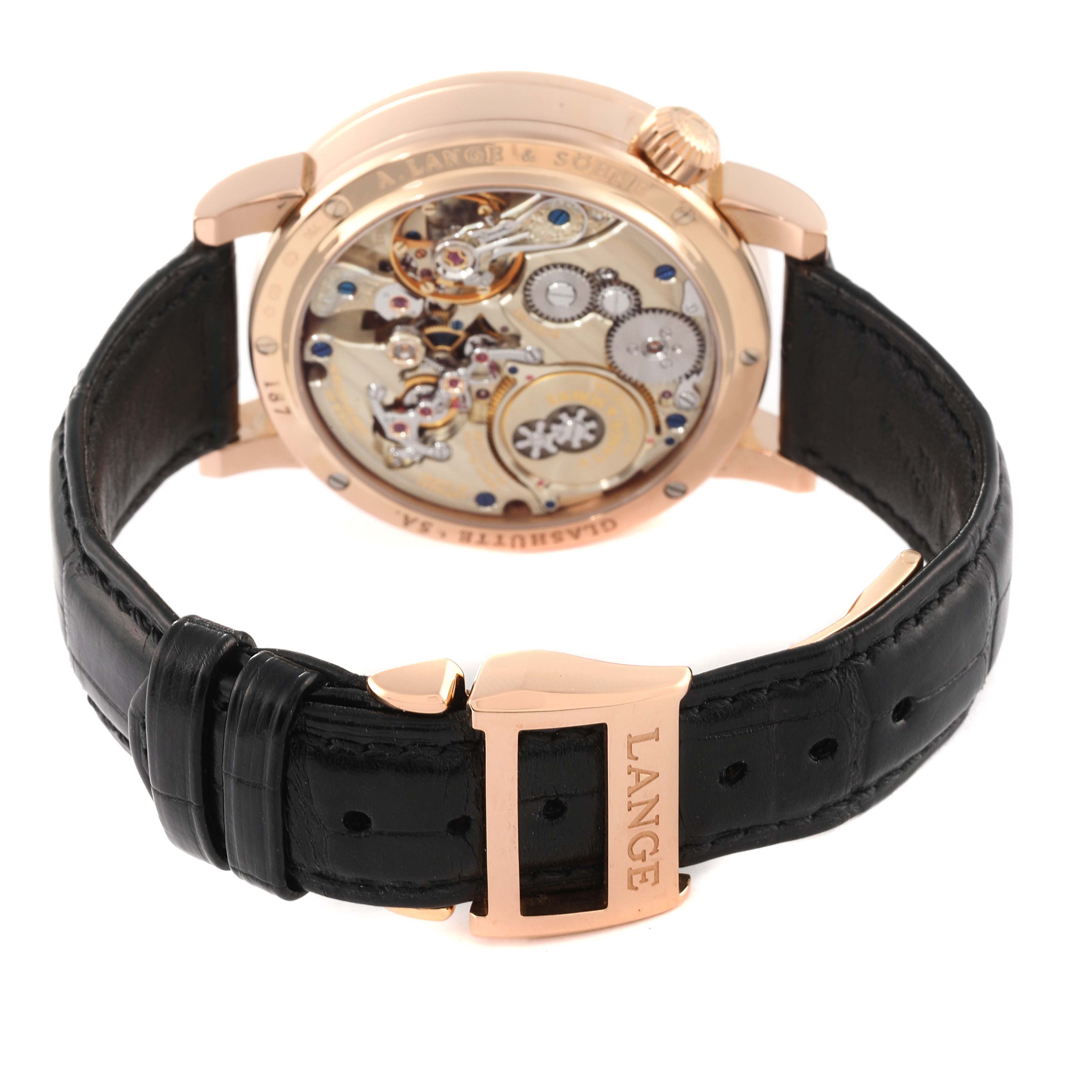 The image shows the back view of the A. Lange & Sohne Zeitwerk watch, revealing its intricate movement and black leather strap with a "LANGE" engraved clasp.