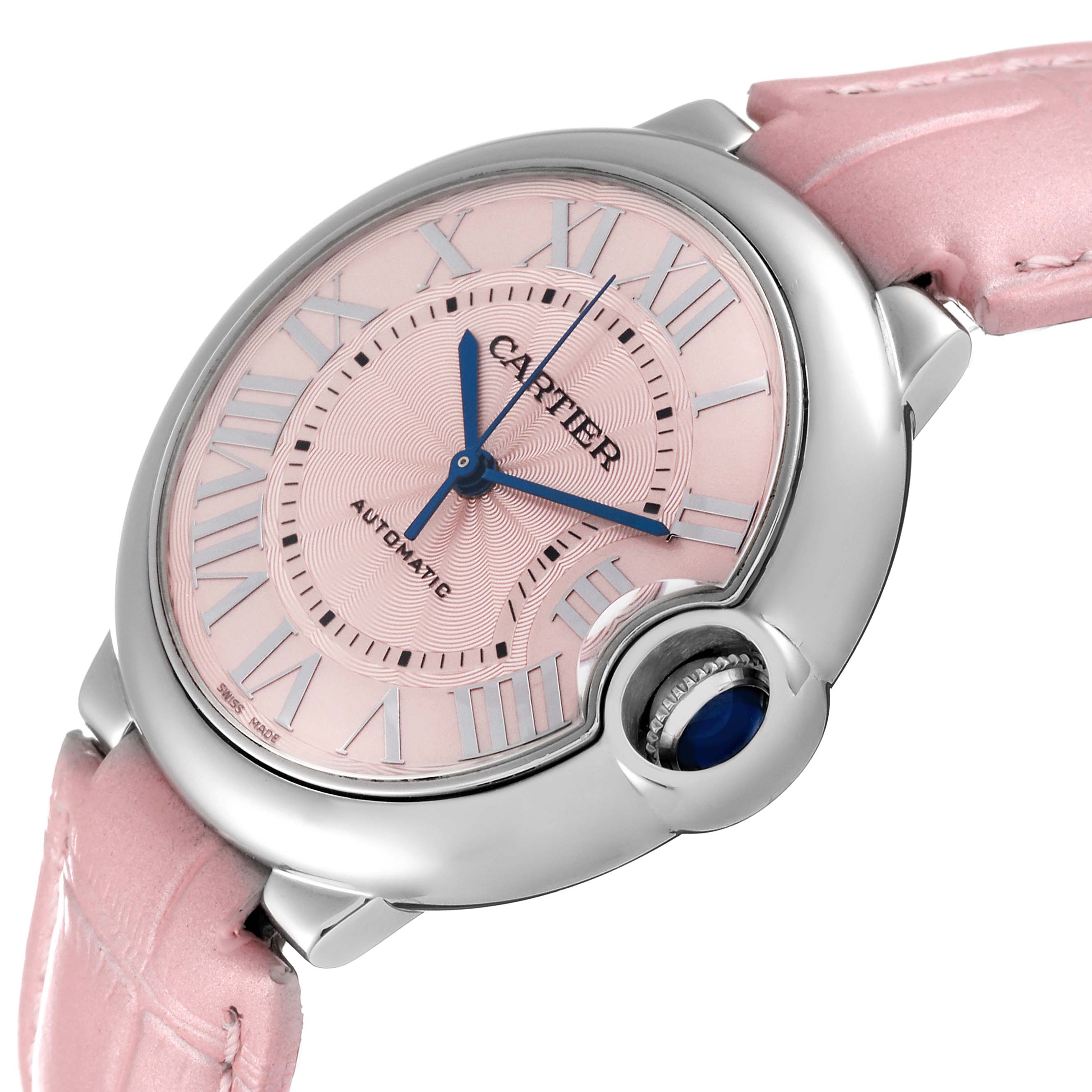 The image shows a Ballon Bleu de Cartier watch from an angled close-up, highlighting its pink dial, blue hands, and crown.