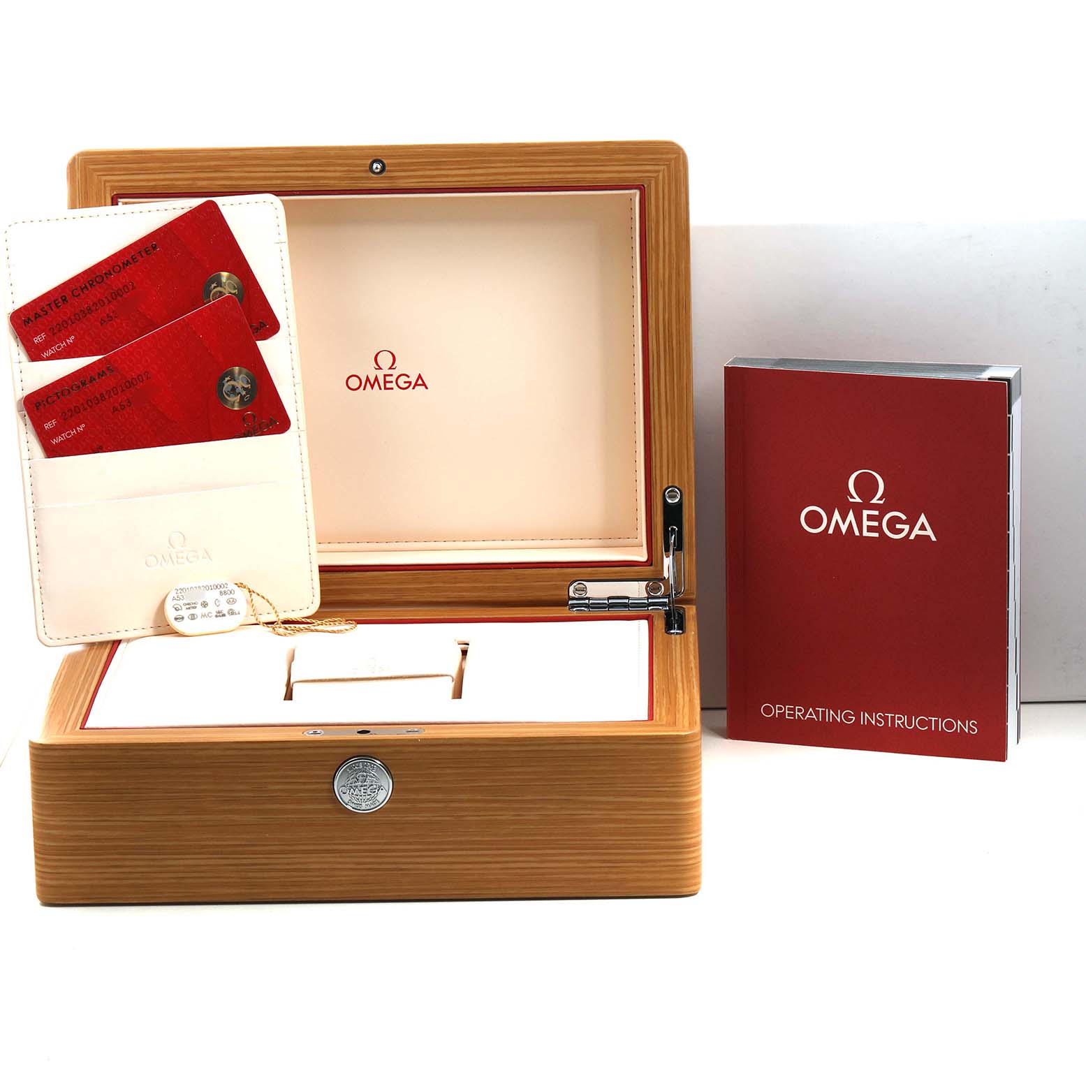 The image shows an angled view of an Omega Seamaster 220.10.38.20.10.002 Men's Stainless Steel Green Dial watch box, cards, a cardholder, and an instruction manual.