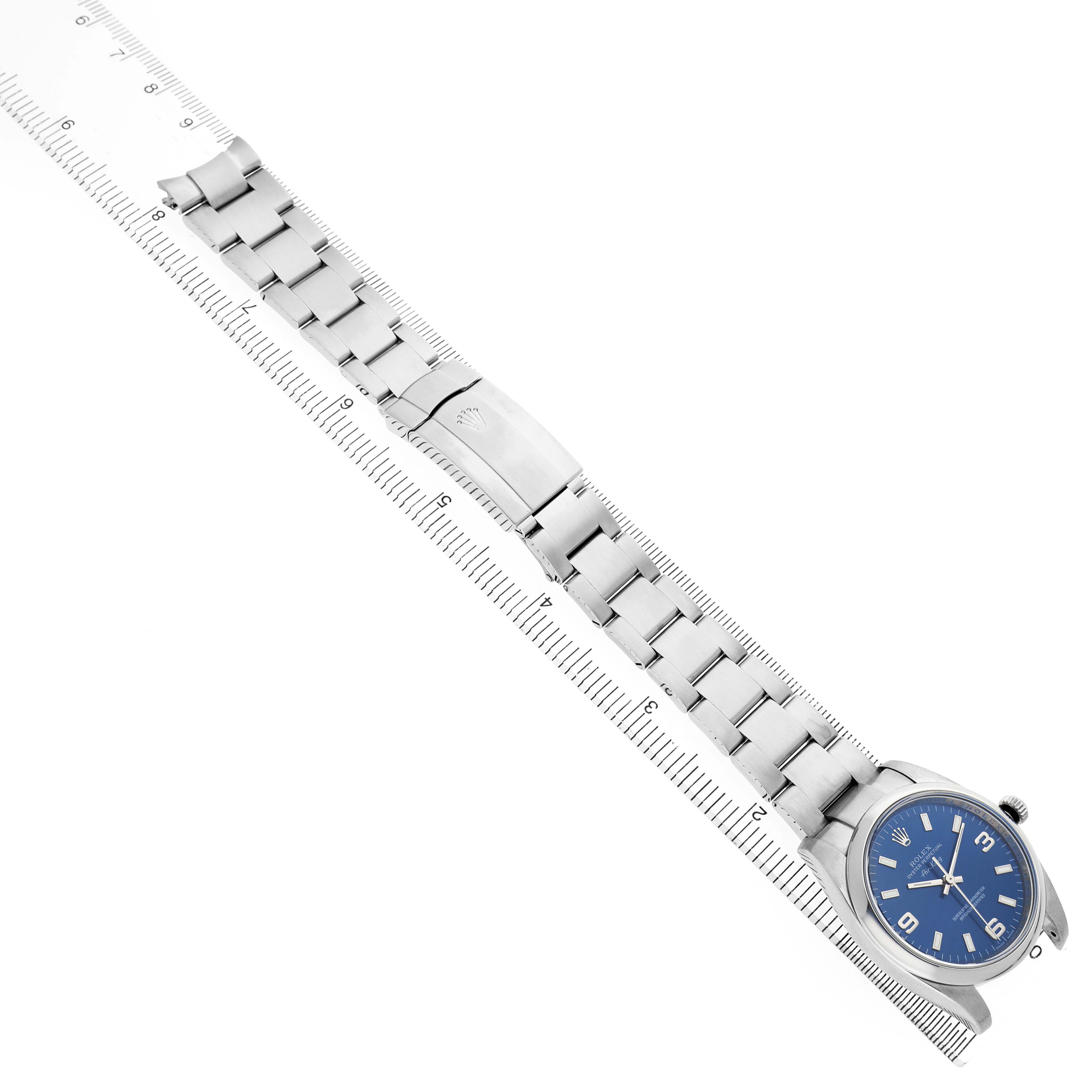 The Rolex Air-King 114200 Men's Stainless Steel Blue Dial watch is displayed diagonally, fully extended, showing the bracelet, clasp, and dial with a ruler for scale.