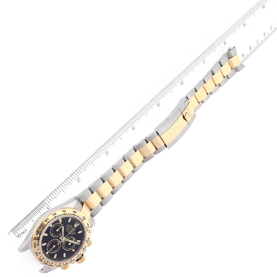 The image shows a Rolex Daytona 116503 Men's Steel and Gold (two tone) Black Dial 116503 Men's Steel and Gold (two tone) Black Dial watch at an angled top-down view, featuring the face, bezel, and two-tone bracelet against a ruler.