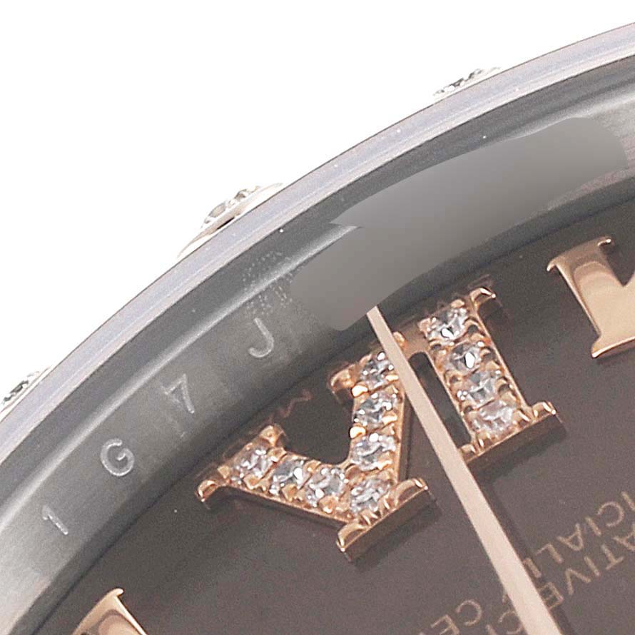 The close-up angle of this Mid-Size Rolex watch shows part of the bezel, dial, and an embellished Roman numeral.