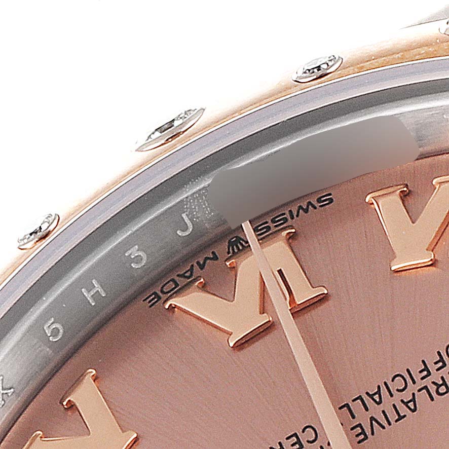 This is a close-up image of a Rolex Mid-Size 278341 Women's Steel and Gold (two tone) Pink Dial 278341 Women's Steel and Gold (two tone) Pink Dial model watch showing part of the bezel and dial with Roman numerals.
