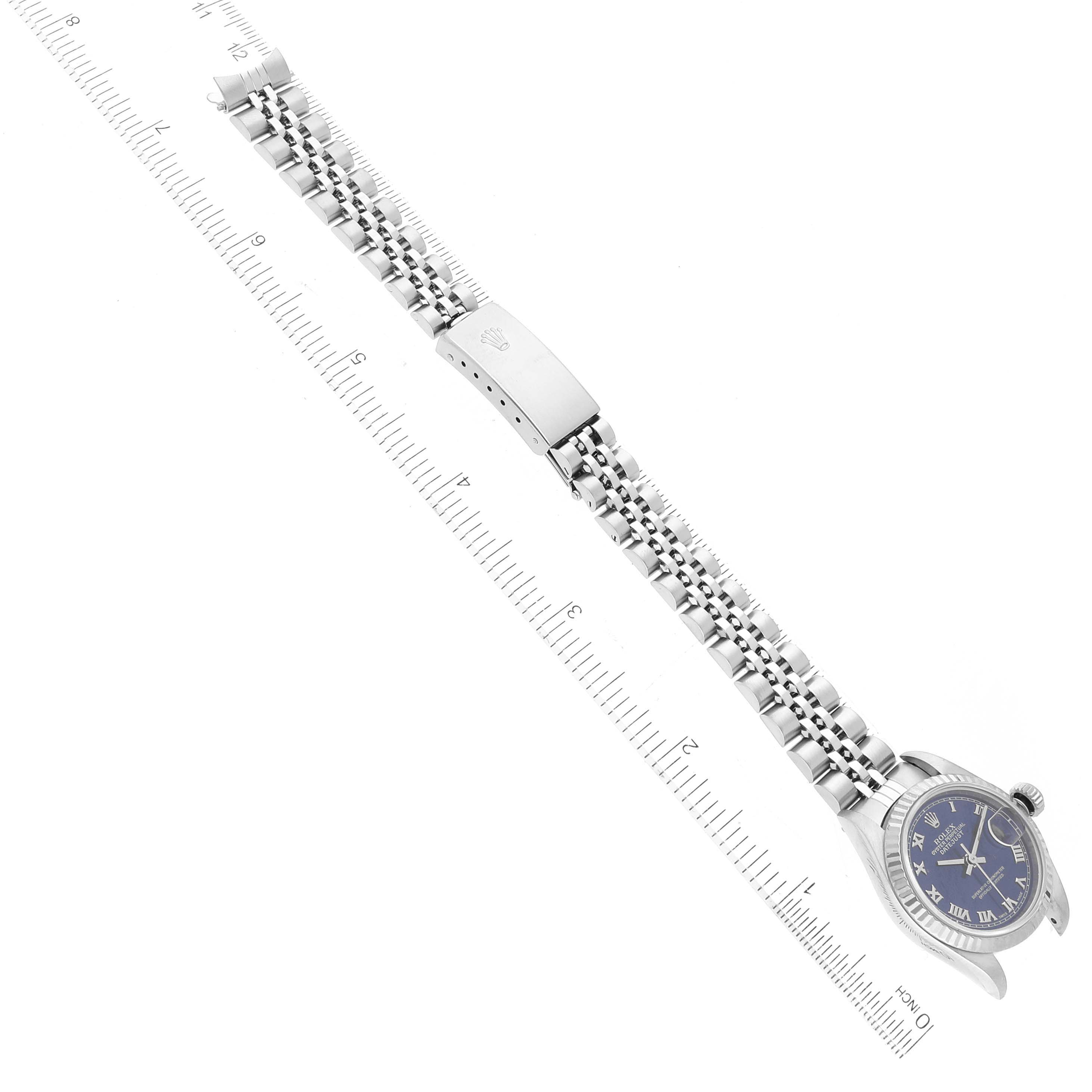 The image shows a Rolex Datejust 79174 Women's Stainless Steel Blue Dial 79174 Women's Stainless Steel Blue Dial watch laid flat with its bracelet extended and a ruler for scale.