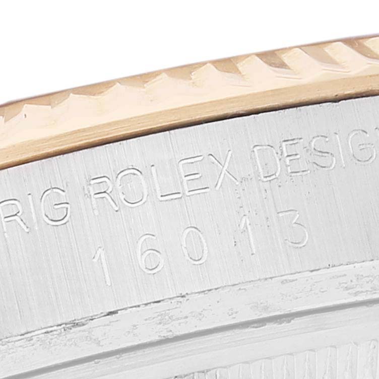 This close-up image shows the fluted bezel and case edge with the engraved serial number of a Rolex Datejust 16013 Men
s Steel and Gold (two tone) Silver Dial 16013 Men
s Steel and Gold (two tone) Silver Dial model.