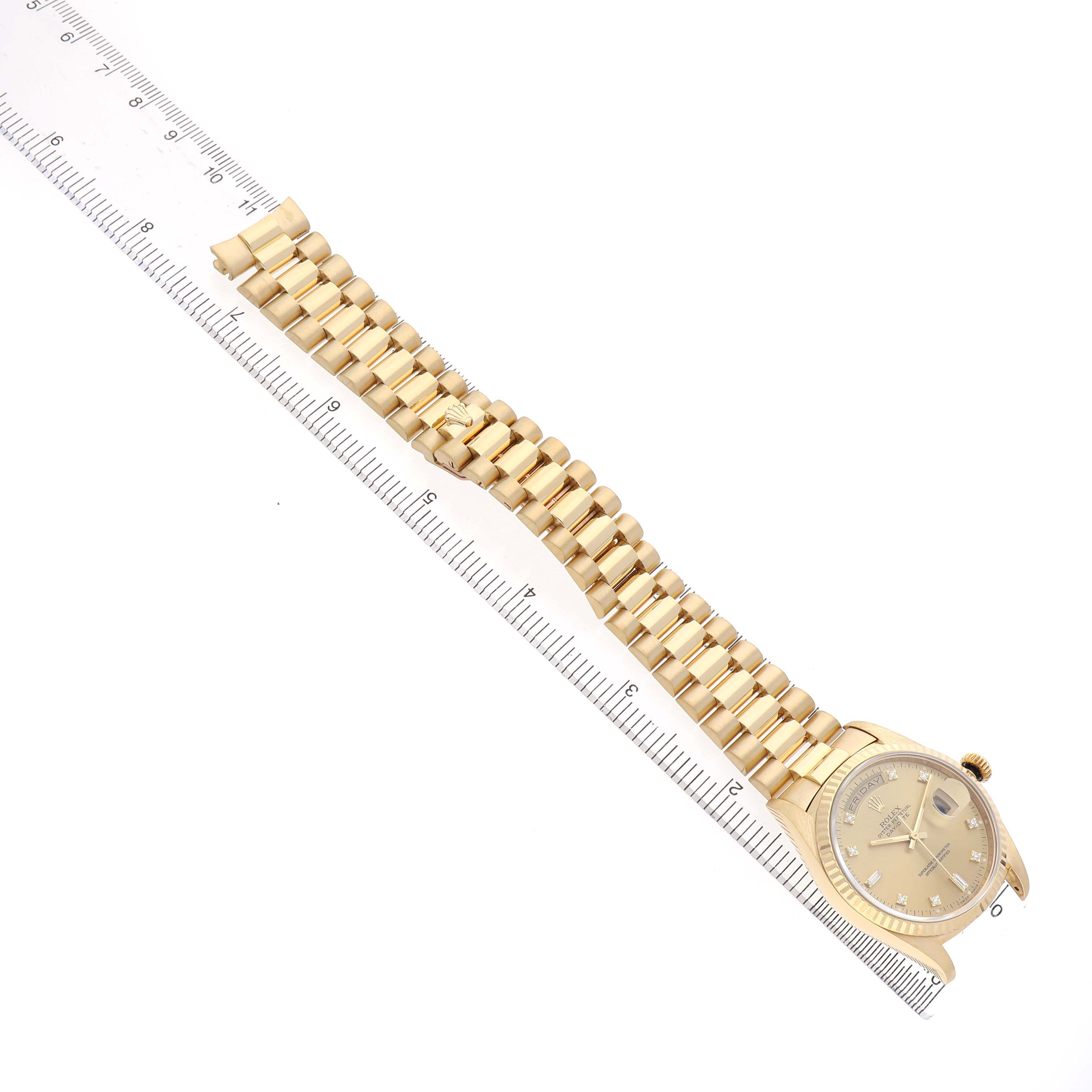 The Rolex President 18238 Men's Yellow Gold Champagne Dial watch is shown at an overhead angle highlighting the gold band and face beside a ruler for scale.