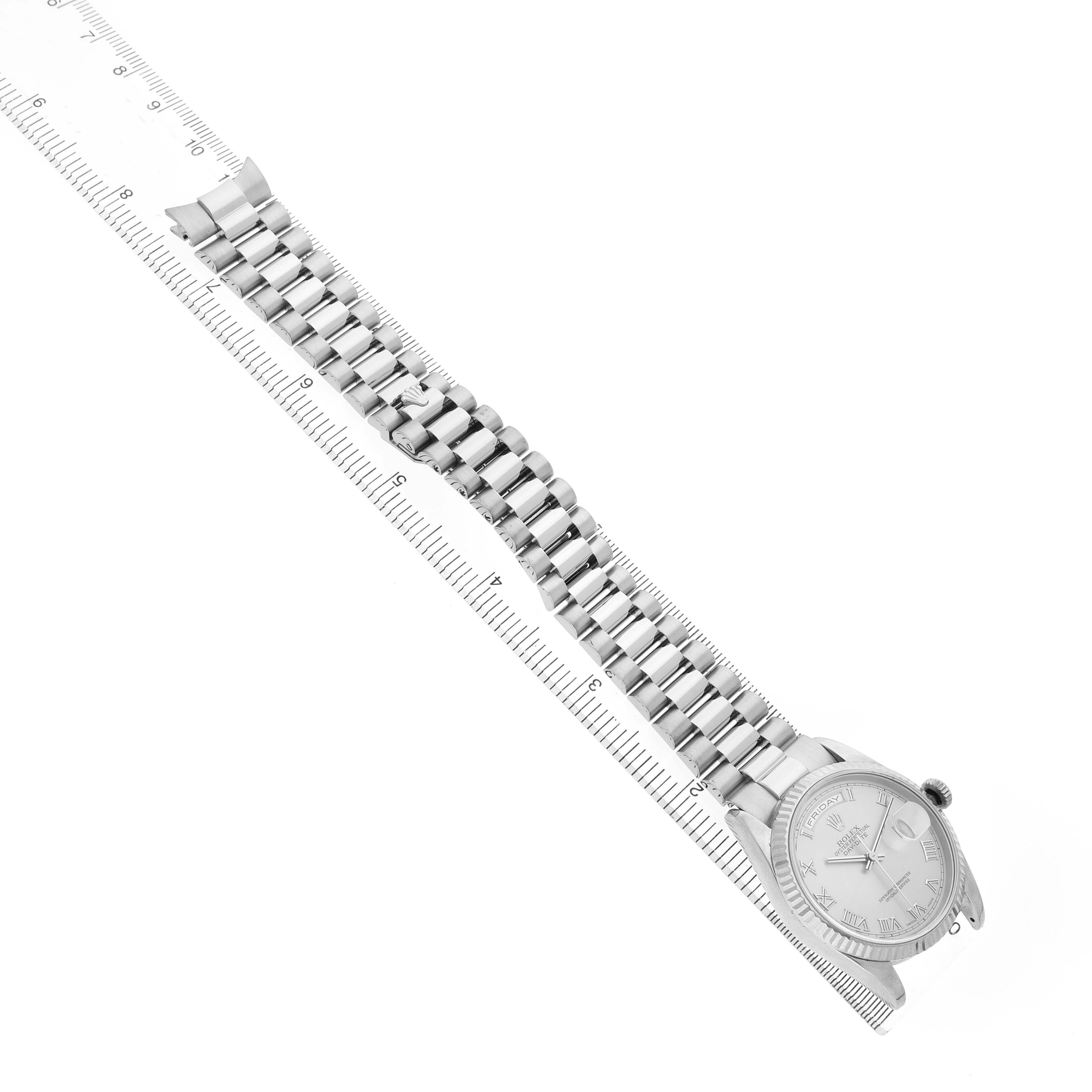 The Rolex President 118209 Men's White Gold Silver Dial model watch is shown from above, highlighting the face and full bracelet, aligned with a ruler.
