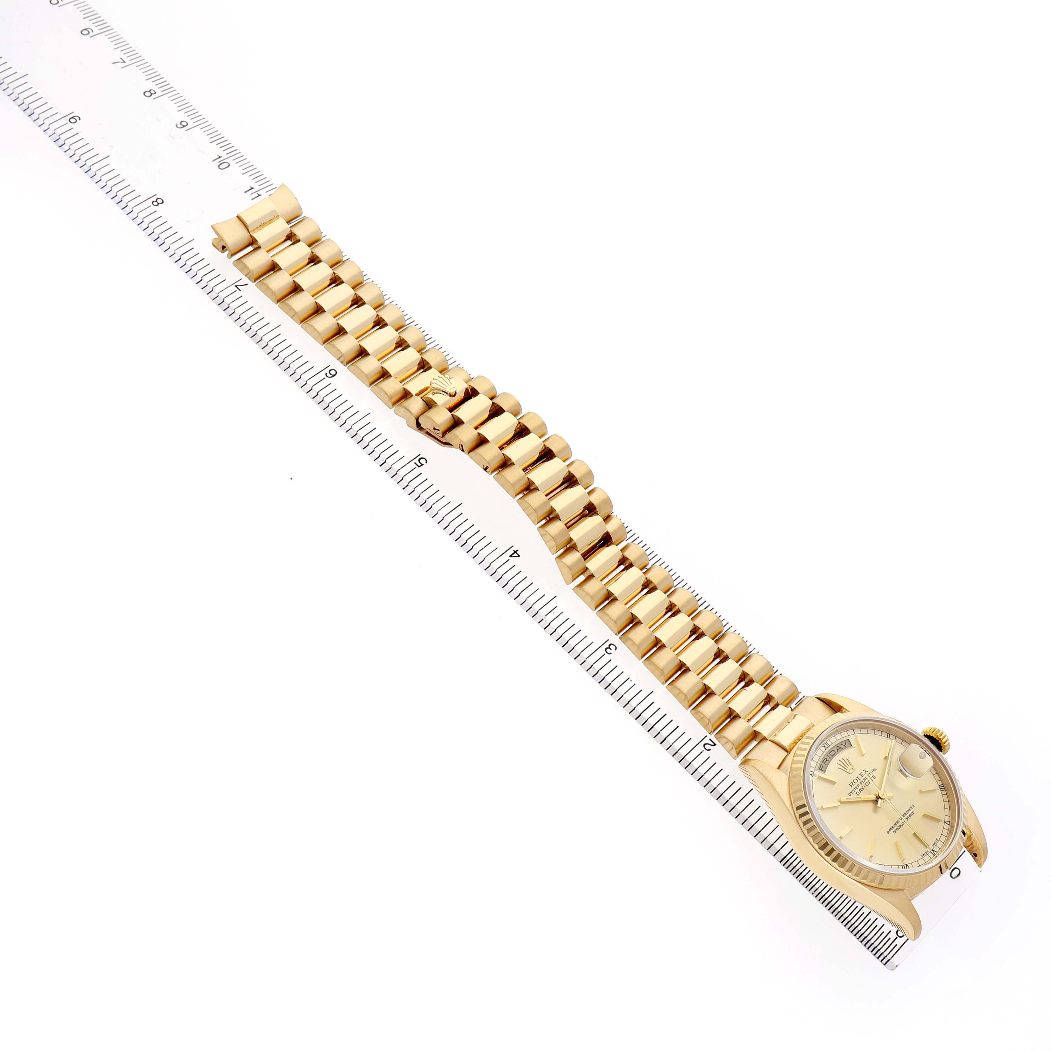 The Rolex President 18238 Men's Yellow Gold Champagne Dial watch is shown at an angle displaying the face, crown, and full gold bracelet, with a ruler for scale.
