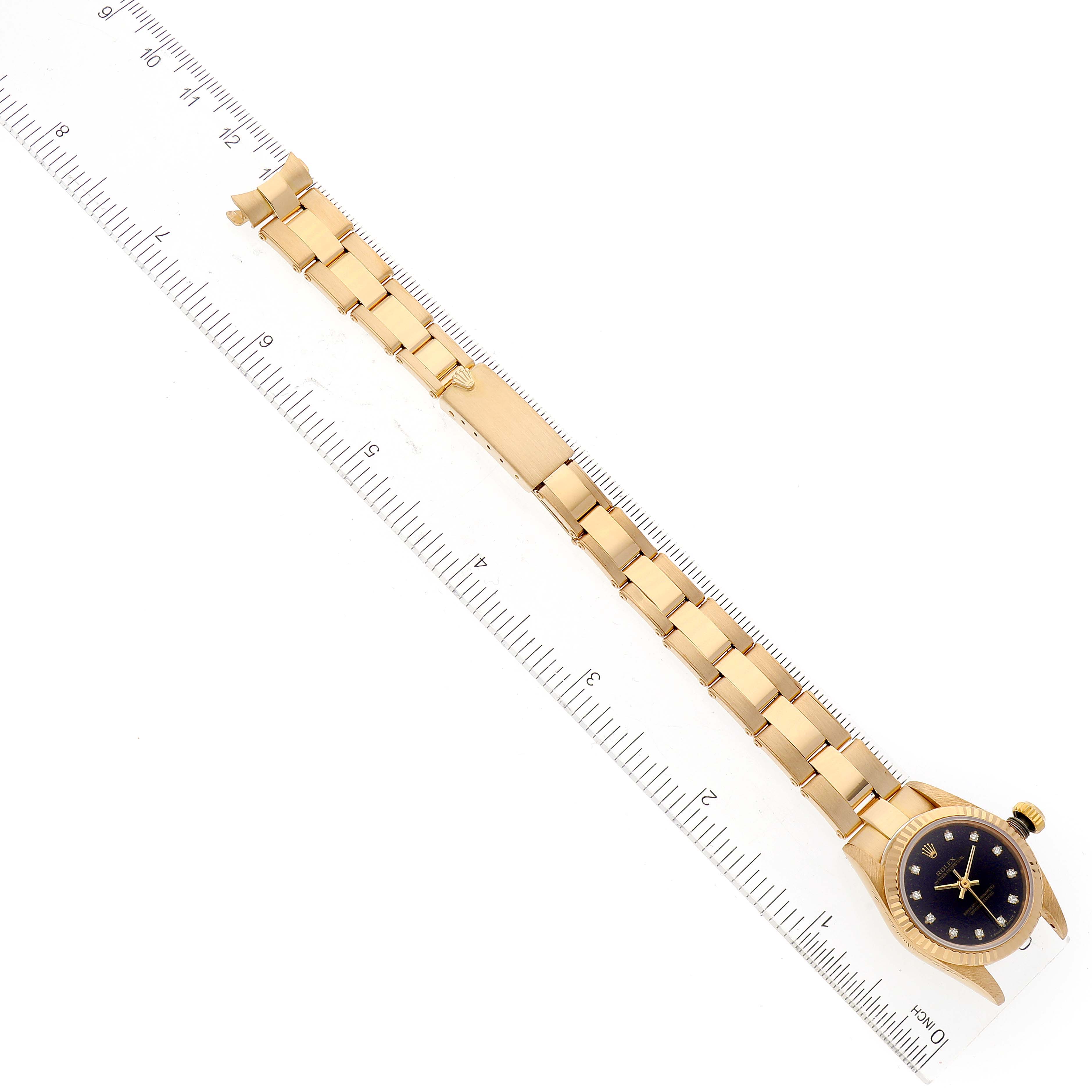 The image shows a Rolex Pearlmaster 67198 Women
s Yellow Gold Black Dial 67198 Women
s Yellow Gold Black Dial watch laid flat alongside a ruler, highlighting the bracelet and face from a top-down angle.