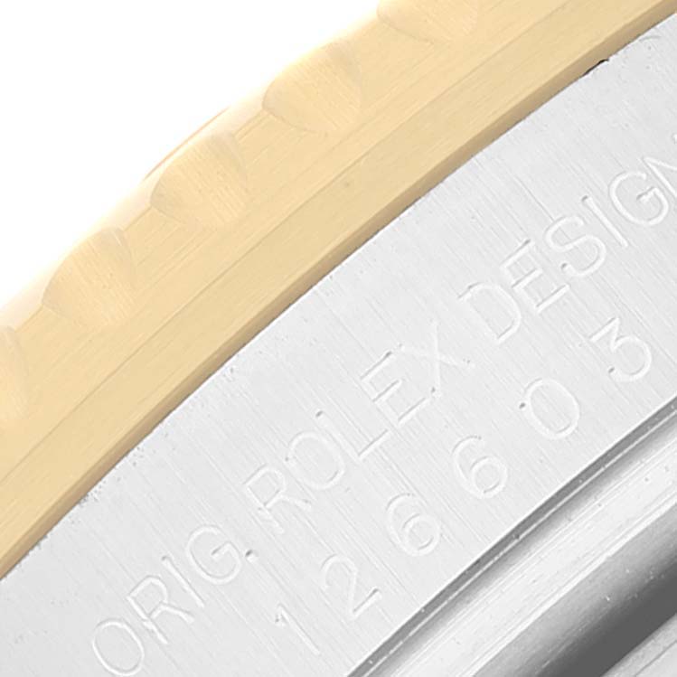 The image shows a close-up of the side of the bezel and the edge of the case back of the Rolex Sea-Dweller 126603 Men's Steel and Gold (two tone) Black Dial 126603 Men's Steel and Gold (two tone) Black Dial model, featuring engraved text.