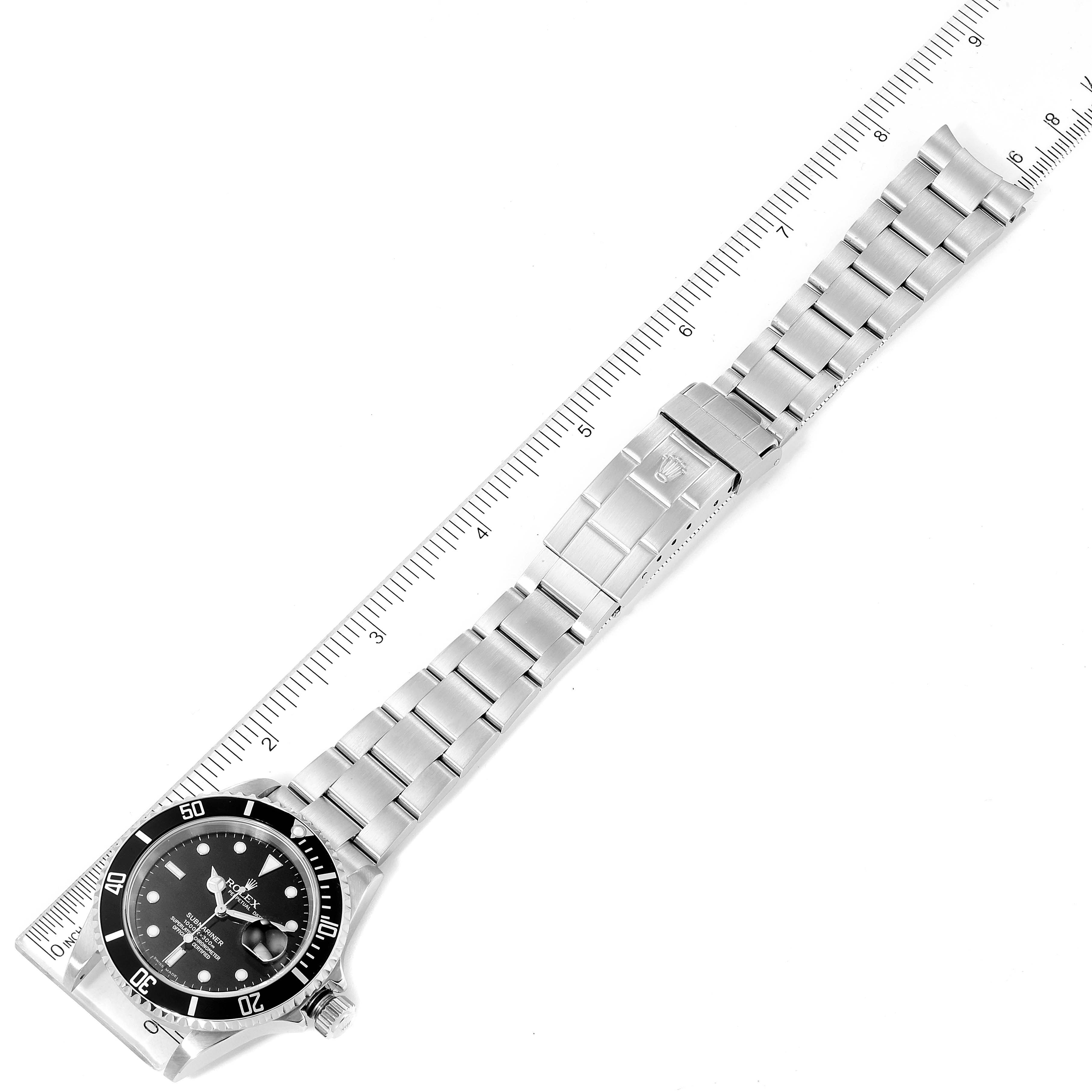 The image shows a top view of a Rolex Submariner 16610 Men's Stainless Steel Black Dial 16610 Men's Stainless Steel Black Dial watch lying flat beside a ruler, displaying its face and metal bracelet.