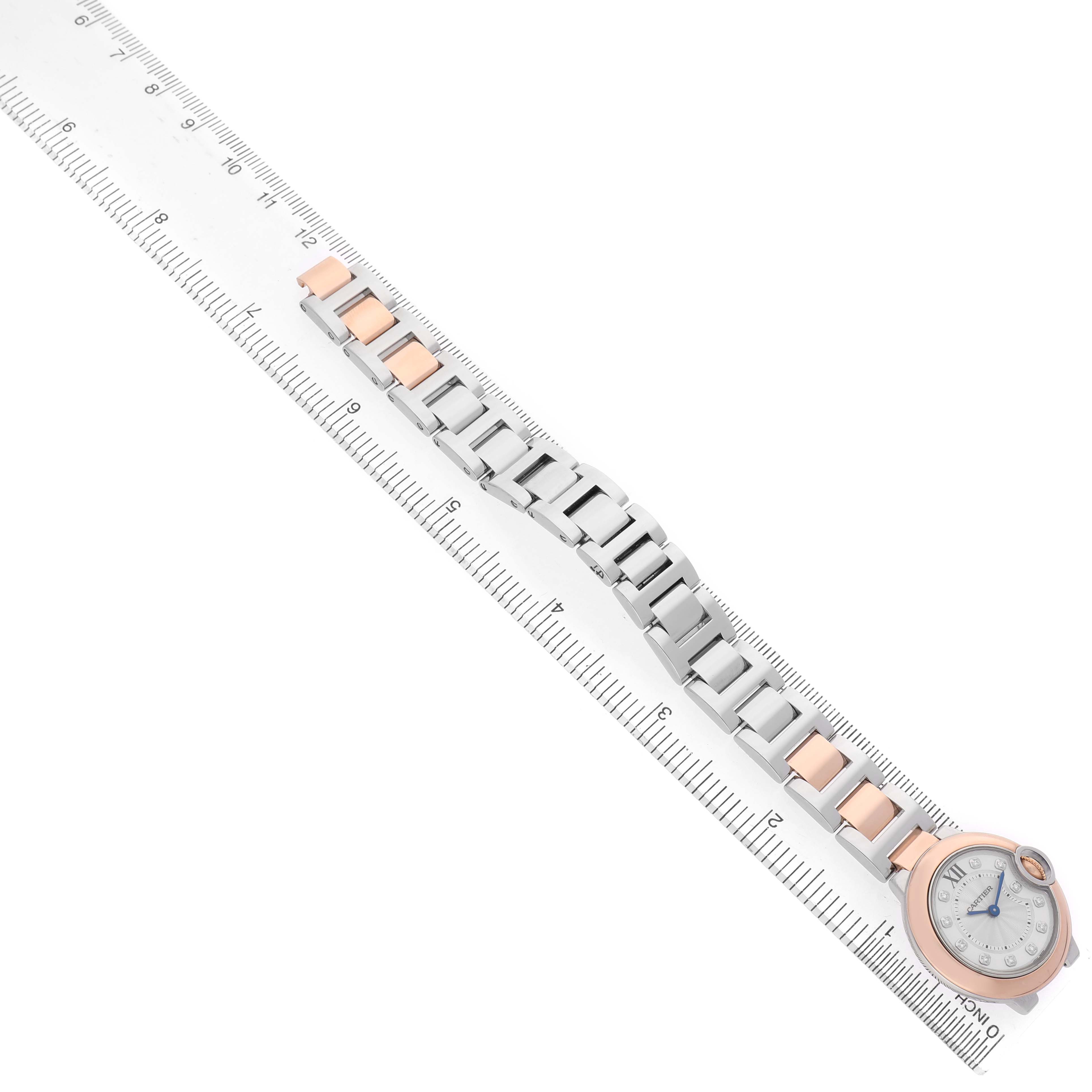 The Cartier Ballon Bleu W3BB0005 Women's Steel and Gold (two tone) Silver Dial watch is shown from a top view, highlighting its stainless steel and rose gold bracelet next to a ruler.