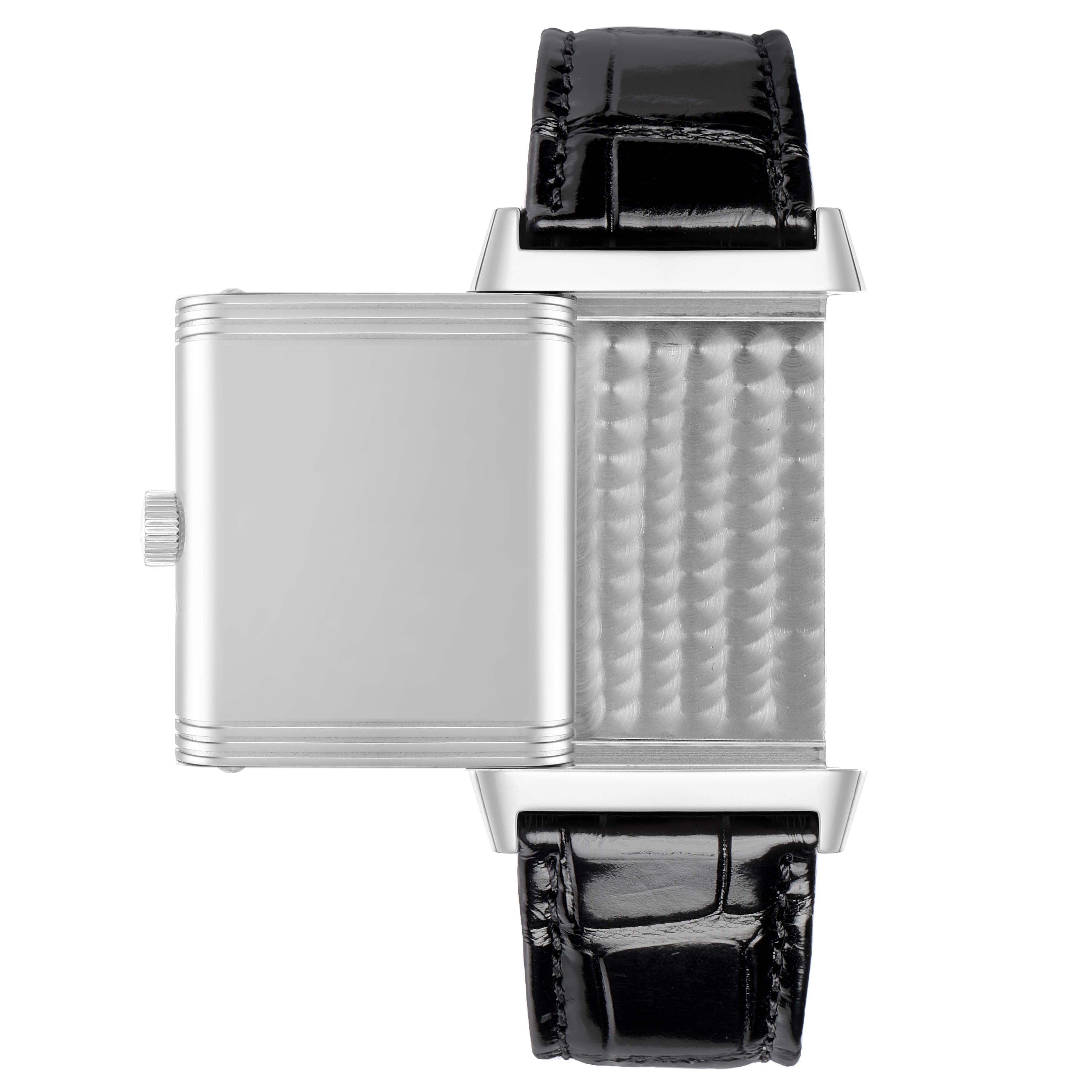 The Jaeger-LeCoultre Reverso watch is shown from the side, with the case flipped open to reveal the intricate metal interior and leather strap.