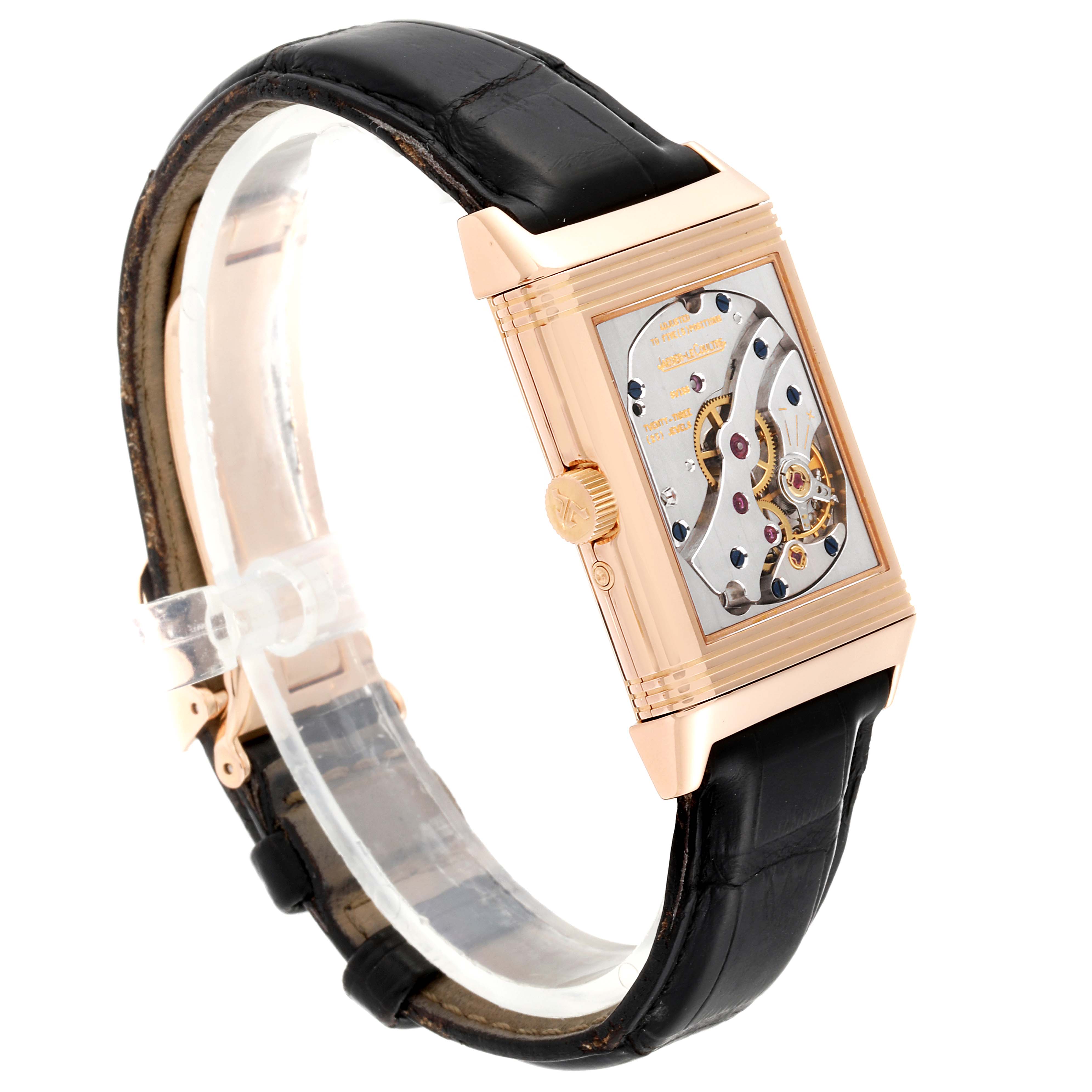 The image shows a side view of a Jaeger-LeCoultre Reverso watch, highlighting its movement and black leather strap.