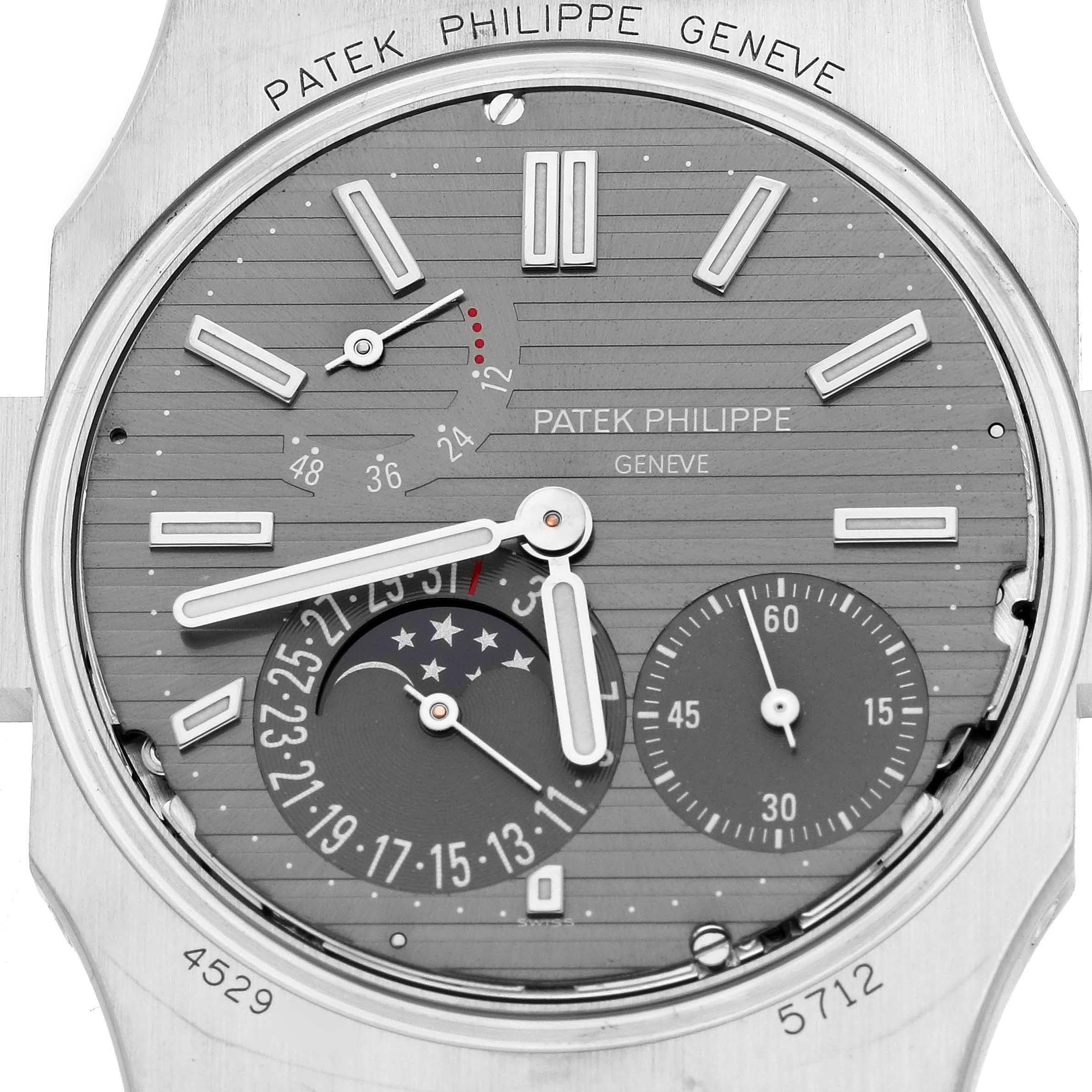 The image shows a close-up of the Patek Philippe Nautilus 5712G Men
s White Gold Grey Dial watch face, highlighting its dials and complications.