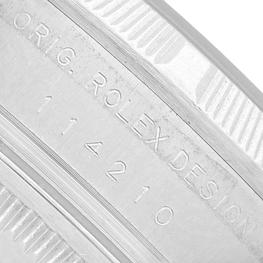 The image shows a close-up of the serial number engraving on the bezel of the Rolex Air-King 114210 Men's Stainless Steel Pink Dial watch.
