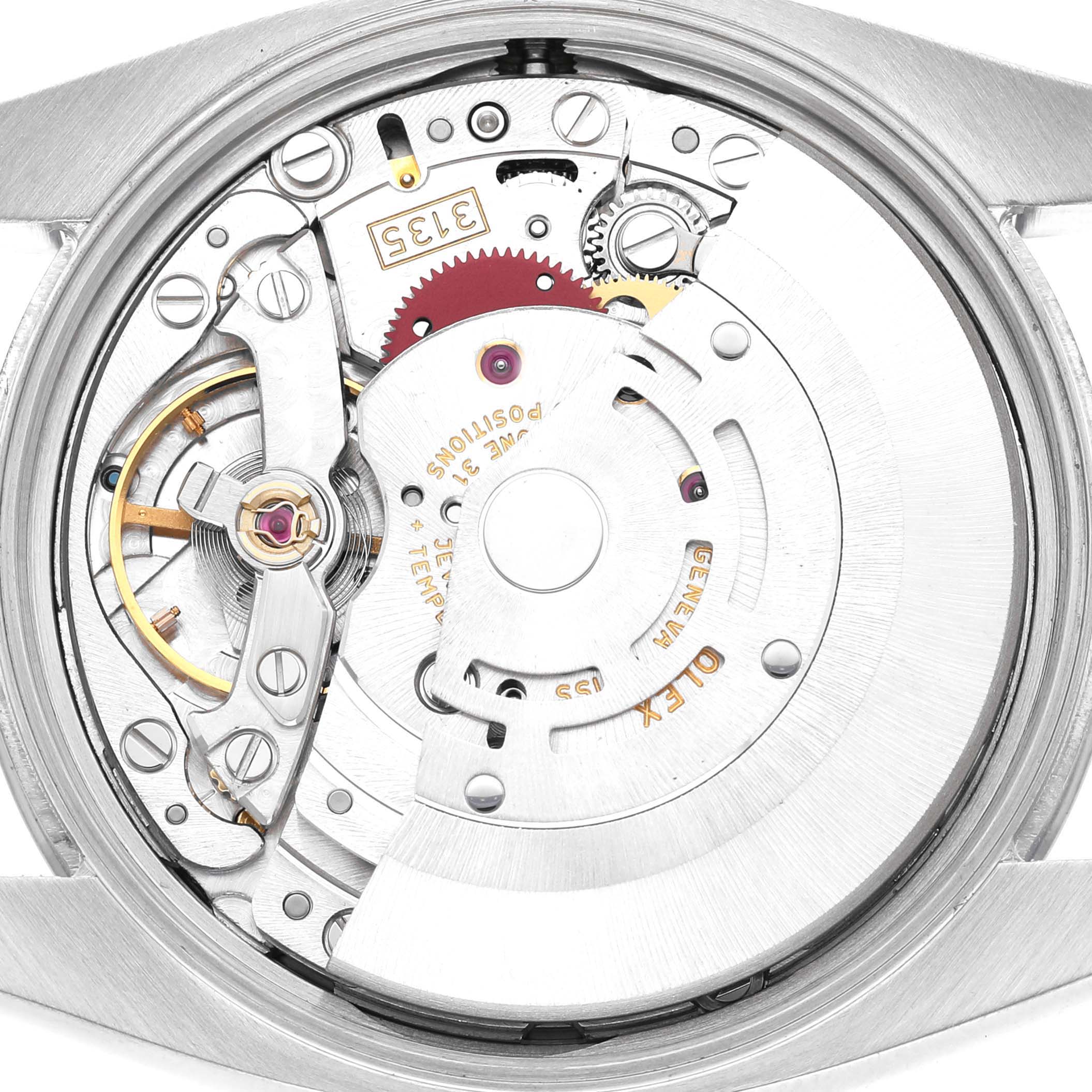 The image shows the movement of a Rolex Date 115210 Men's Stainless Steel Black Dial watch from the back, highlighting gears and mechanical components.