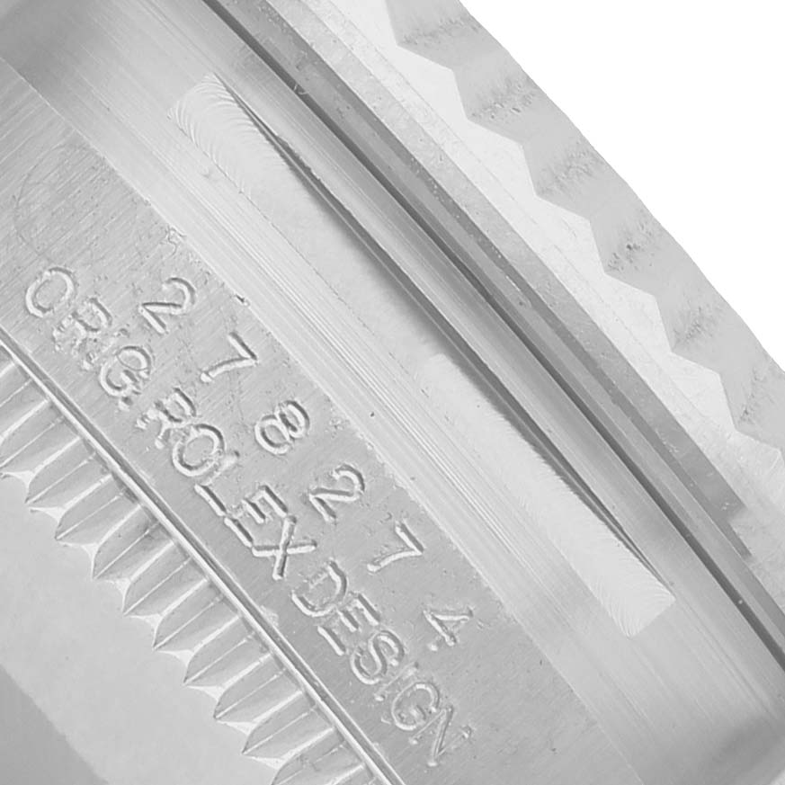 The image shows a close-up of the engraving on the case of a Mid-Size Rolex watch, revealing the serial number and design markings.