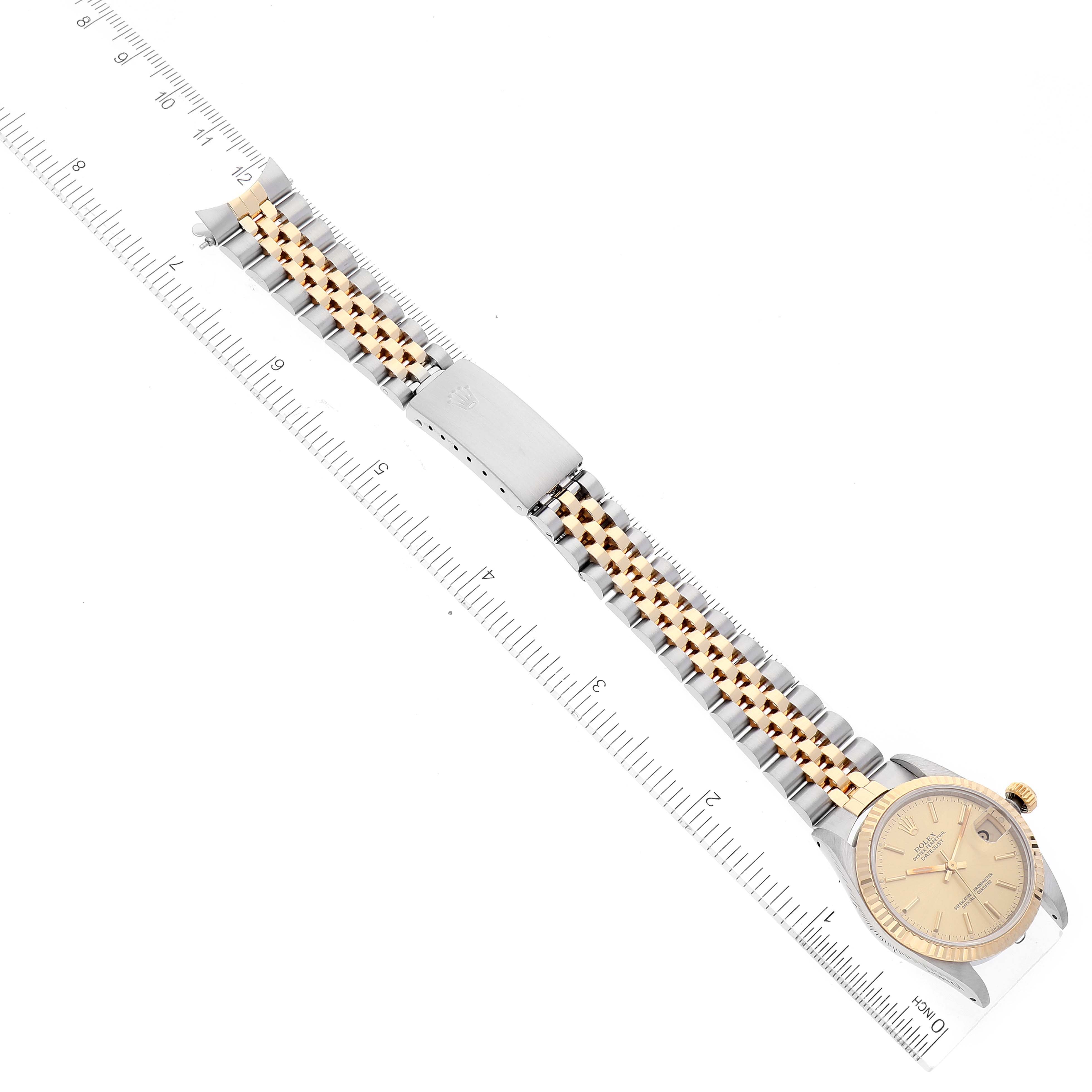 The Rolex Mid-Size 68273 Women
s Steel and Gold (two tone) Champagne Dial 68273 Women
s Steel and Gold (two tone) Champagne Dial model watch is shown from a top-down angle, displaying the entire bracelet, clasp, and face alongside a ruler.