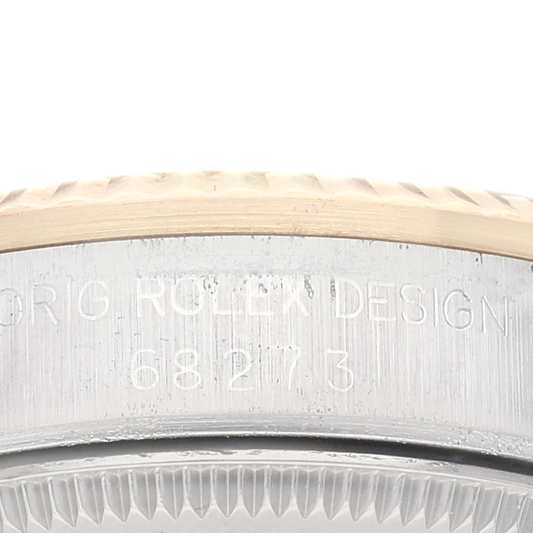 The image shows a close-up of the edge and bezel of a Mid-Size Rolex watch, featuring engraved text and part of the crown.