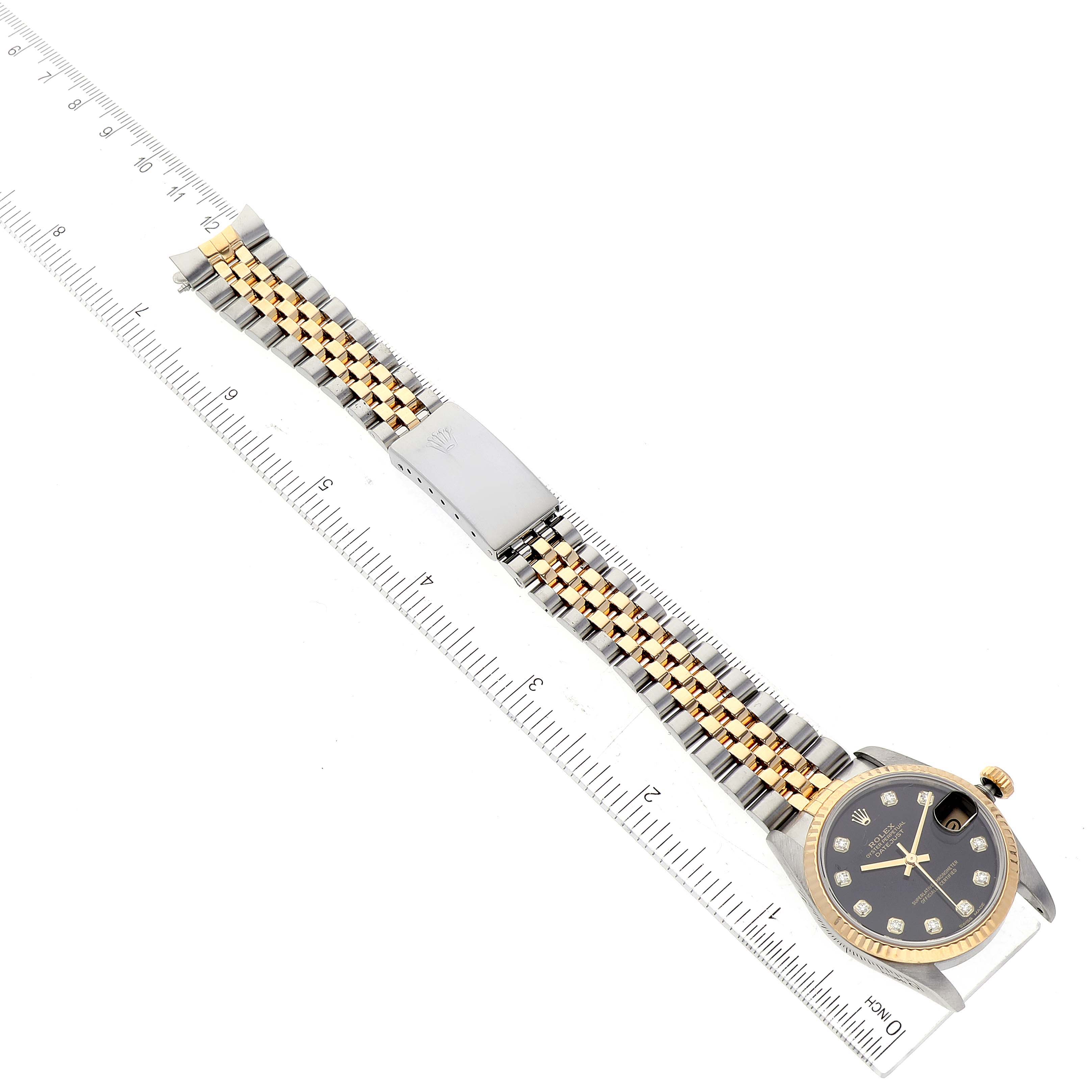 The image shows a Mid-Size Rolex watch laid flat, with a focus on the face and bracelet, against a ruler for scale.