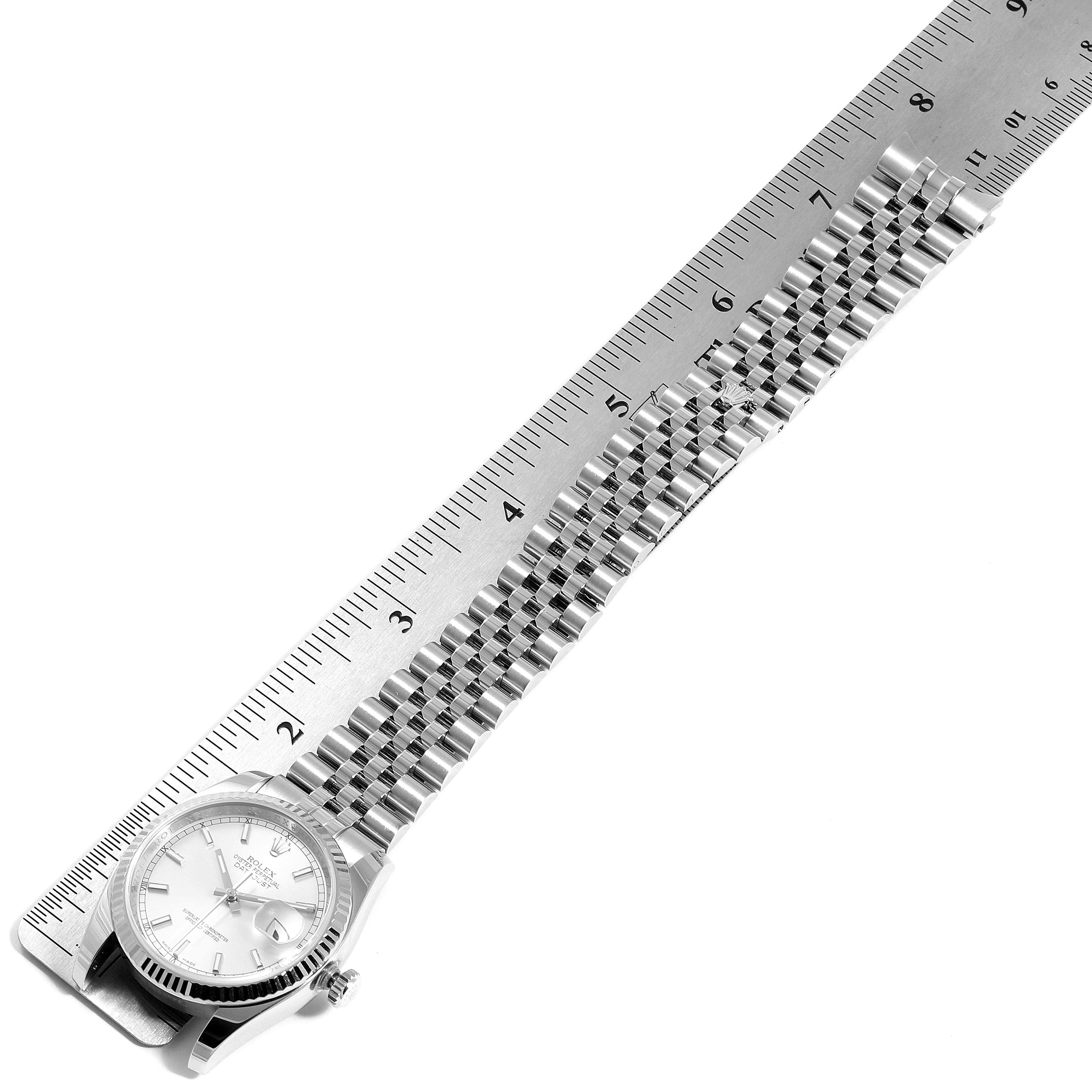 This image shows a Rolex Datejust 116234 Men's Stainless Steel Silver Dial 116234 Men's Stainless Steel Silver Dial watch lying flat next to a ruler, displaying the face, bezel, and band.