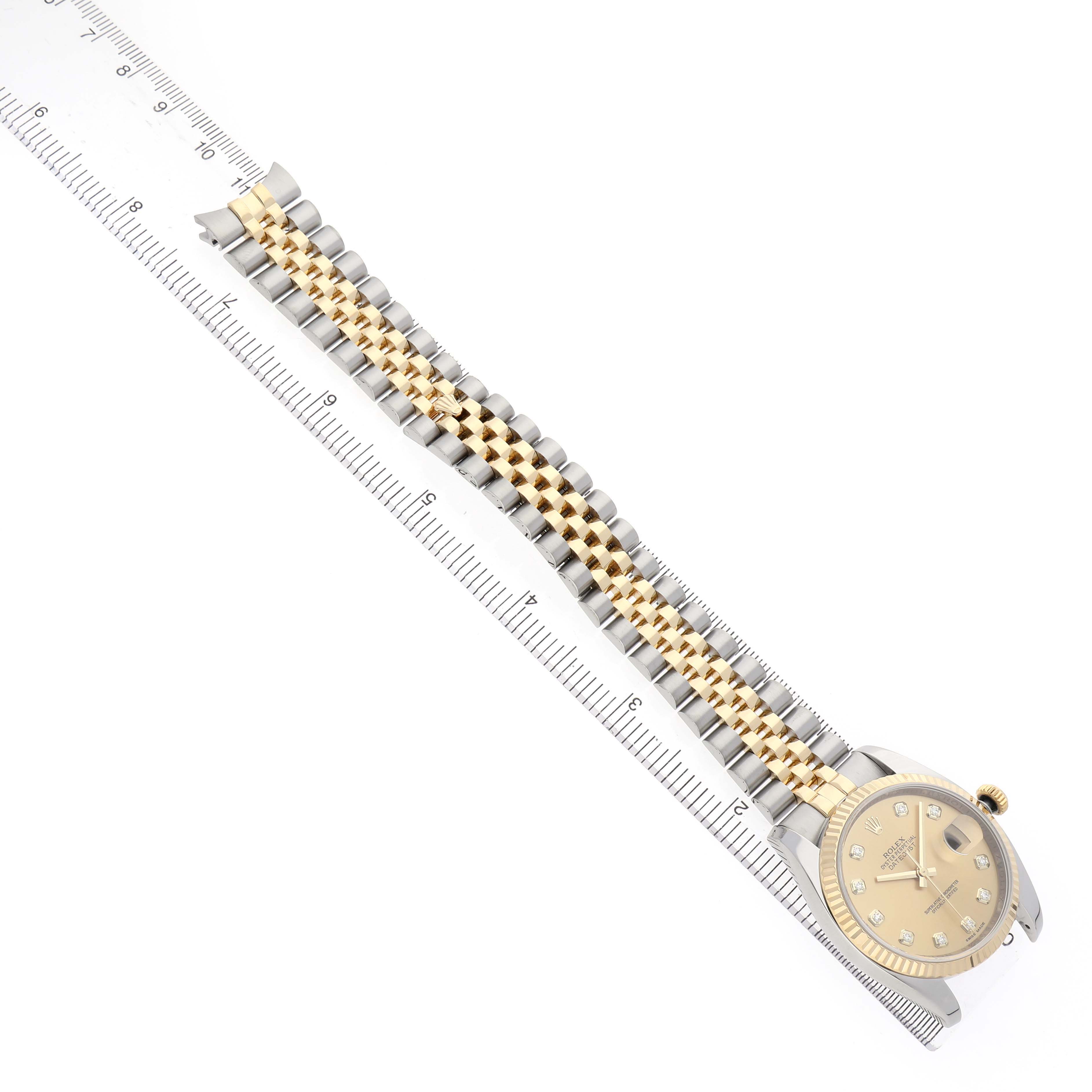 The Rolex Datejust 116233 Men's Steel and Gold (two tone) Champagne Dial watch is shown at a top-down angle, displaying its face and full two-tone bracelet alongside a ruler.