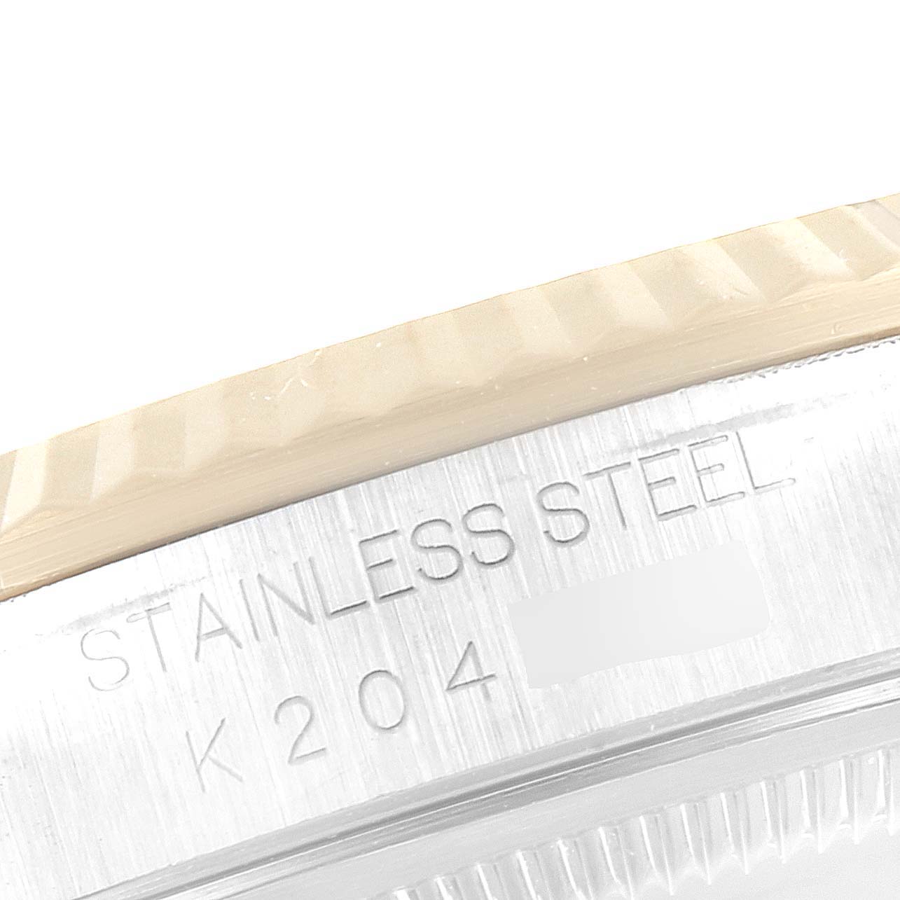 This close-up image of a Rolex Datejust 16233 Men's Steel and Gold (two tone) White Dial 16233 Men's Steel and Gold (two tone) White Dial watch shows part of the fluted bezel and stainless steel inscription.