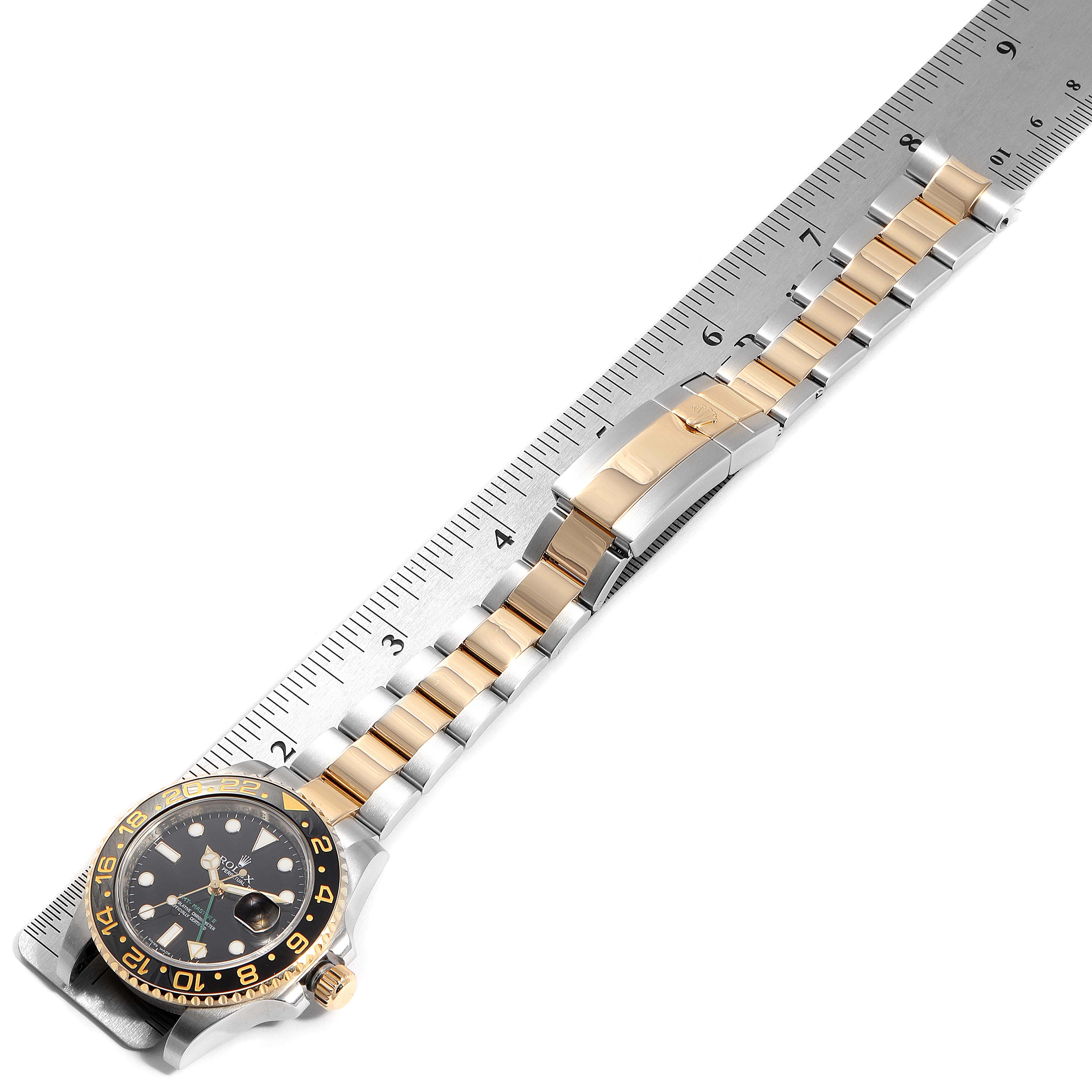 The Rolex GMT-Master 116713 Men's Steel and Gold (two tone) Black Dial 116713 Men's Steel and Gold (two tone) Black Dial watch is shown at a diagonal angle with the full bracelet and some of the bezel visible, placed next to a ruler.