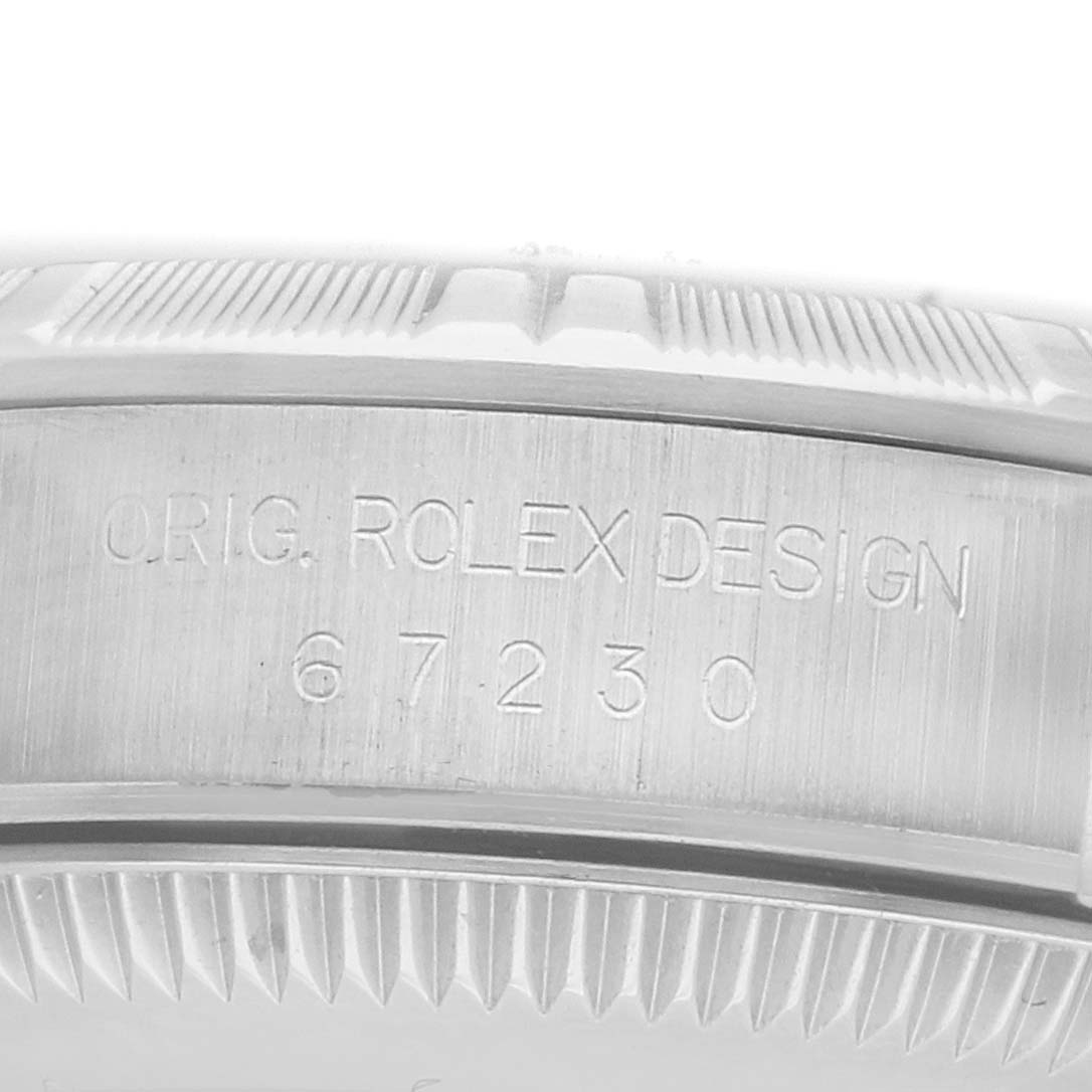 The image shows the side view of a Rolex Oyster Perpetual 67230 Women
s Stainless Steel Black Dial watch case with engraved text and design elements.