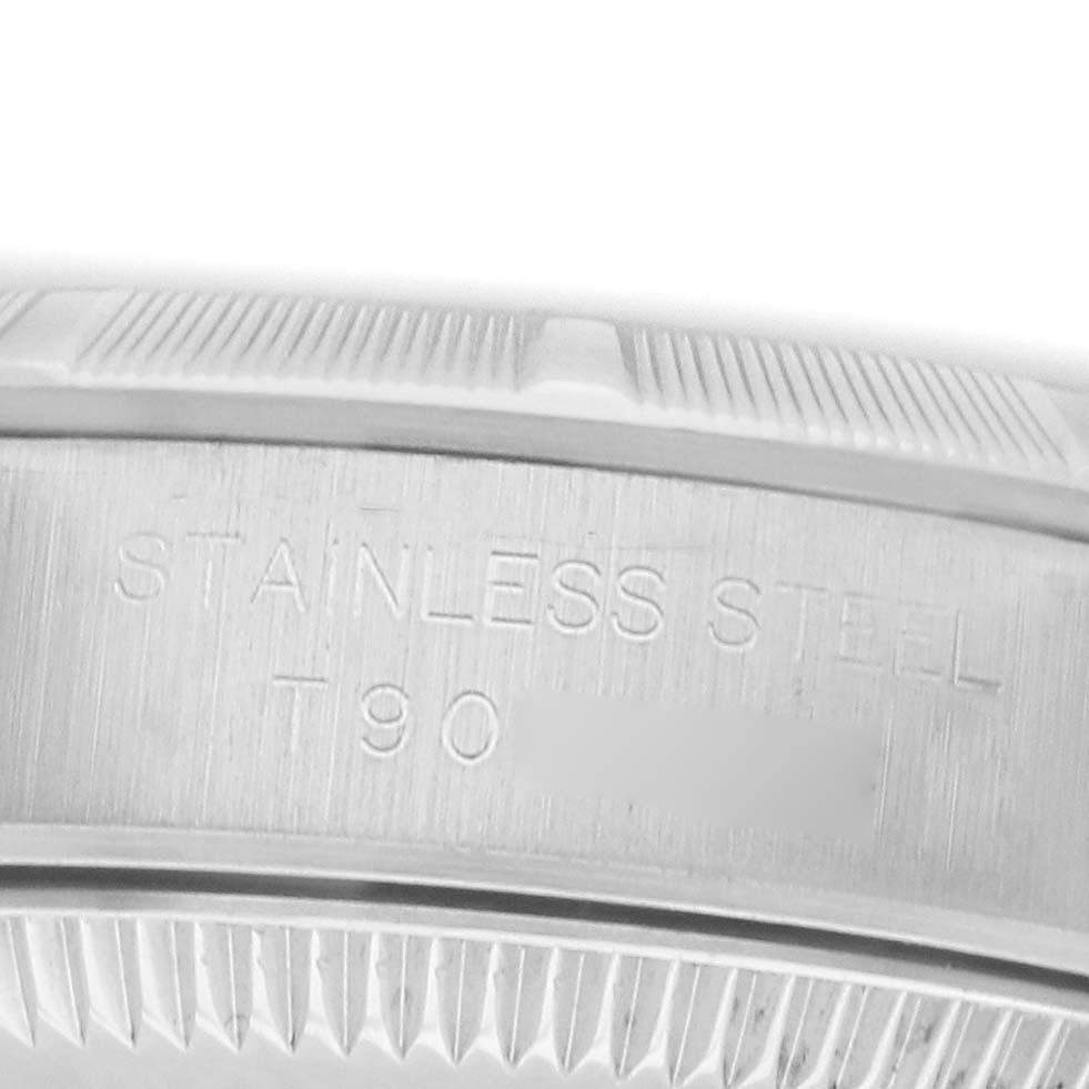 The image shows a close-up of the stainless steel case back of a Rolex Oyster Perpetual 67230 Women
s Stainless Steel Black Dial watch, highlighting engraved details.