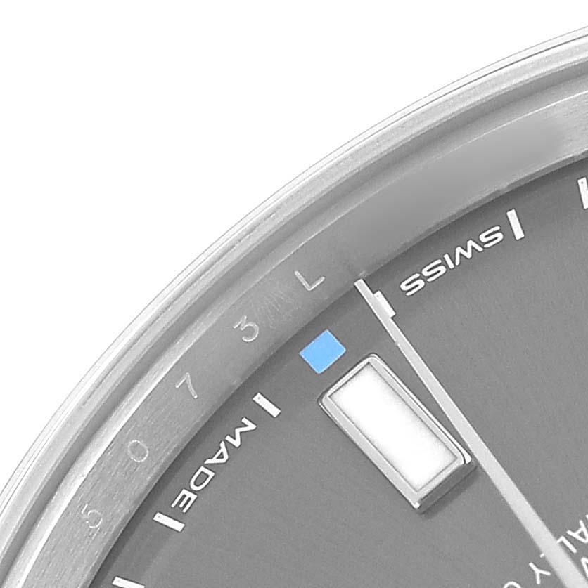 The image shows a close-up of the Rolex Oyster Perpetual 114300 Men's Stainless Steel Grey Dial watch face, highlighting the dial, markers, and part of the bezel.