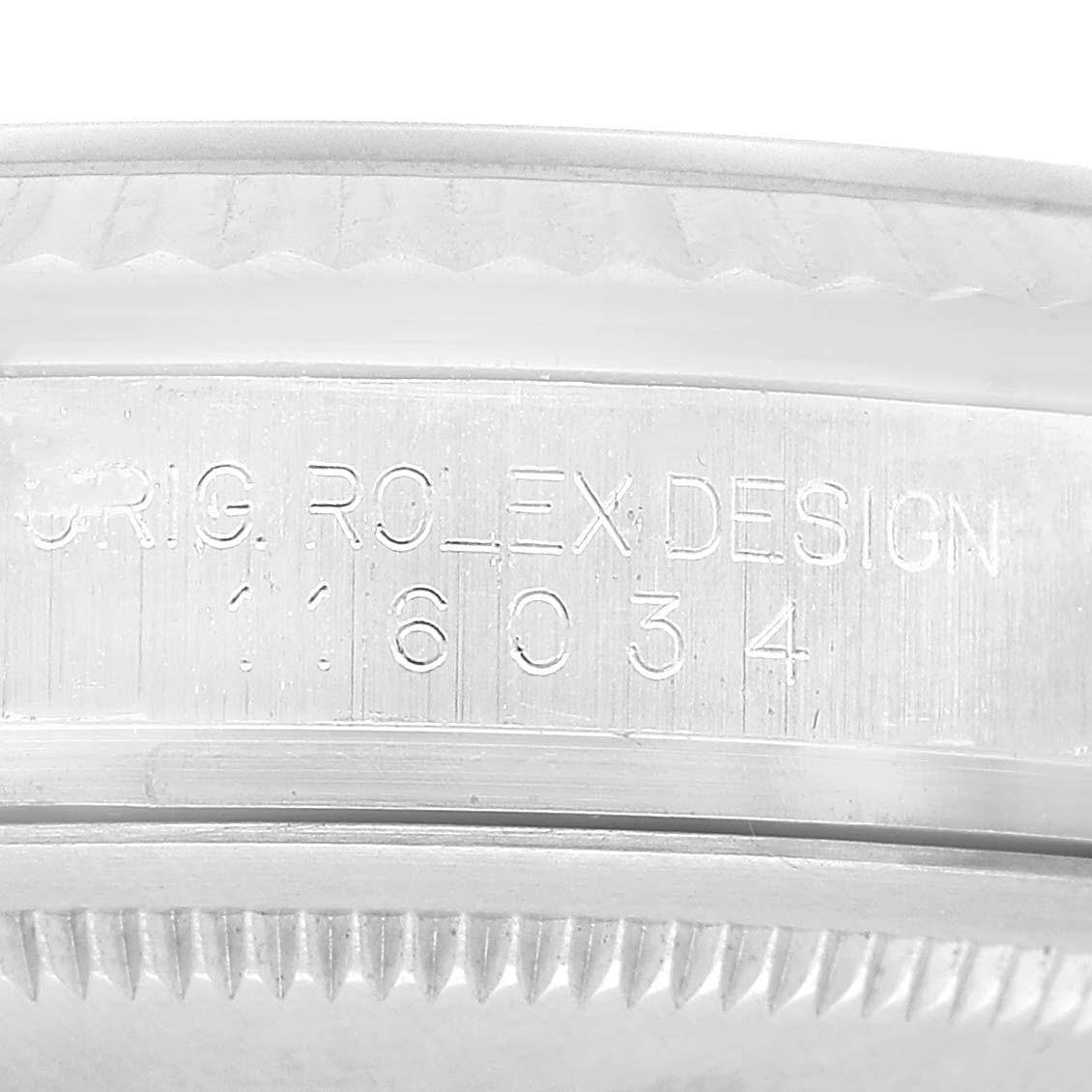 The image shows the side of a Rolex Oyster Perpetual 116034 Men's Stainless Steel Silver Dial, focusing on the engraved serial number and rim details.