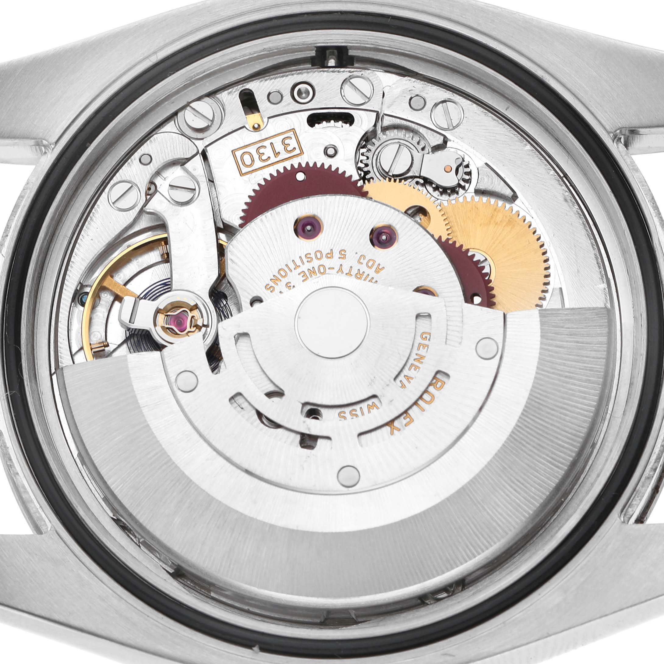 The image shows the internal movement of a Rolex Oyster Perpetual 116034 Men's Stainless Steel Silver Dial watch, viewed from the back, displaying gears and mechanical components.