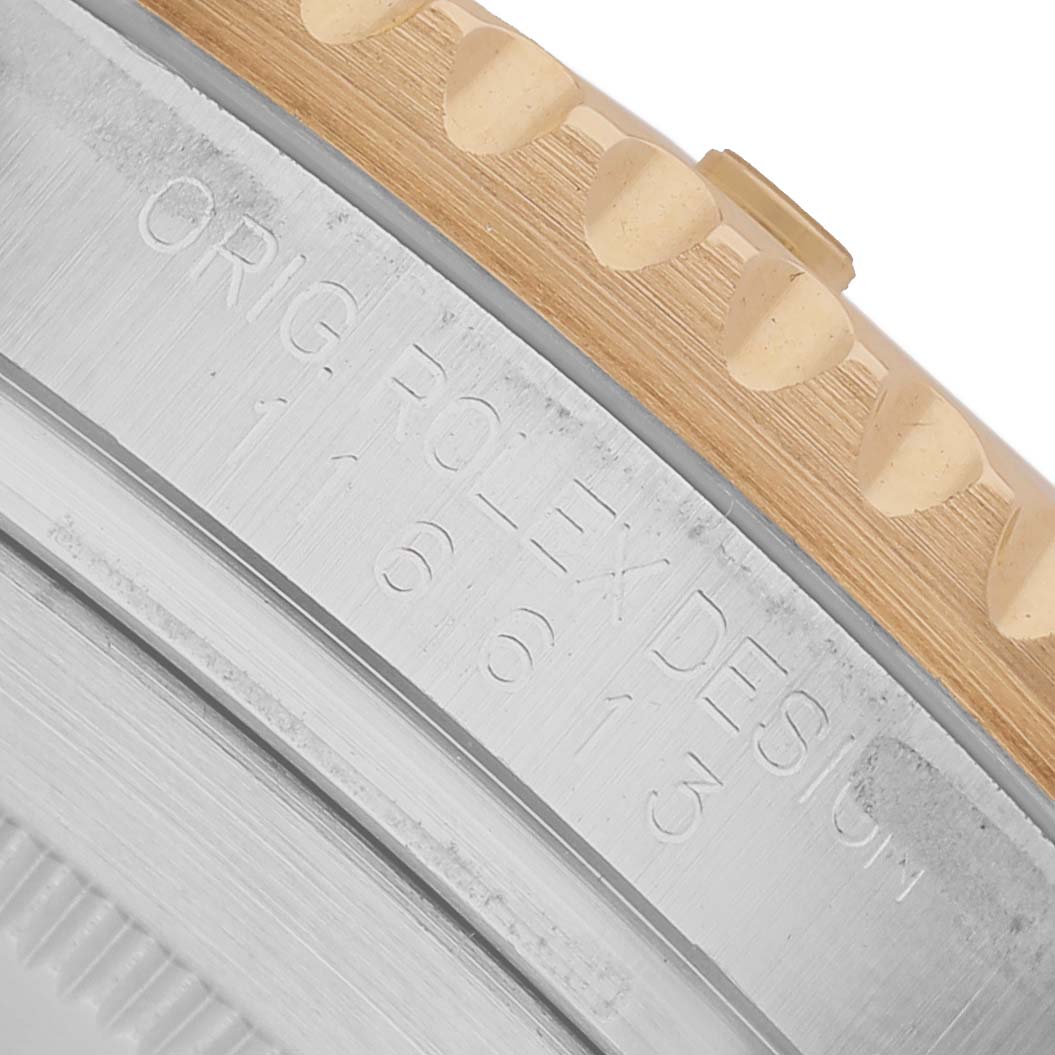 The image shows a close-up of the side engraving and the bezel edge of a Rolex Submariner 116613 Men's Steel and Gold (two tone) Black Dial watch.
