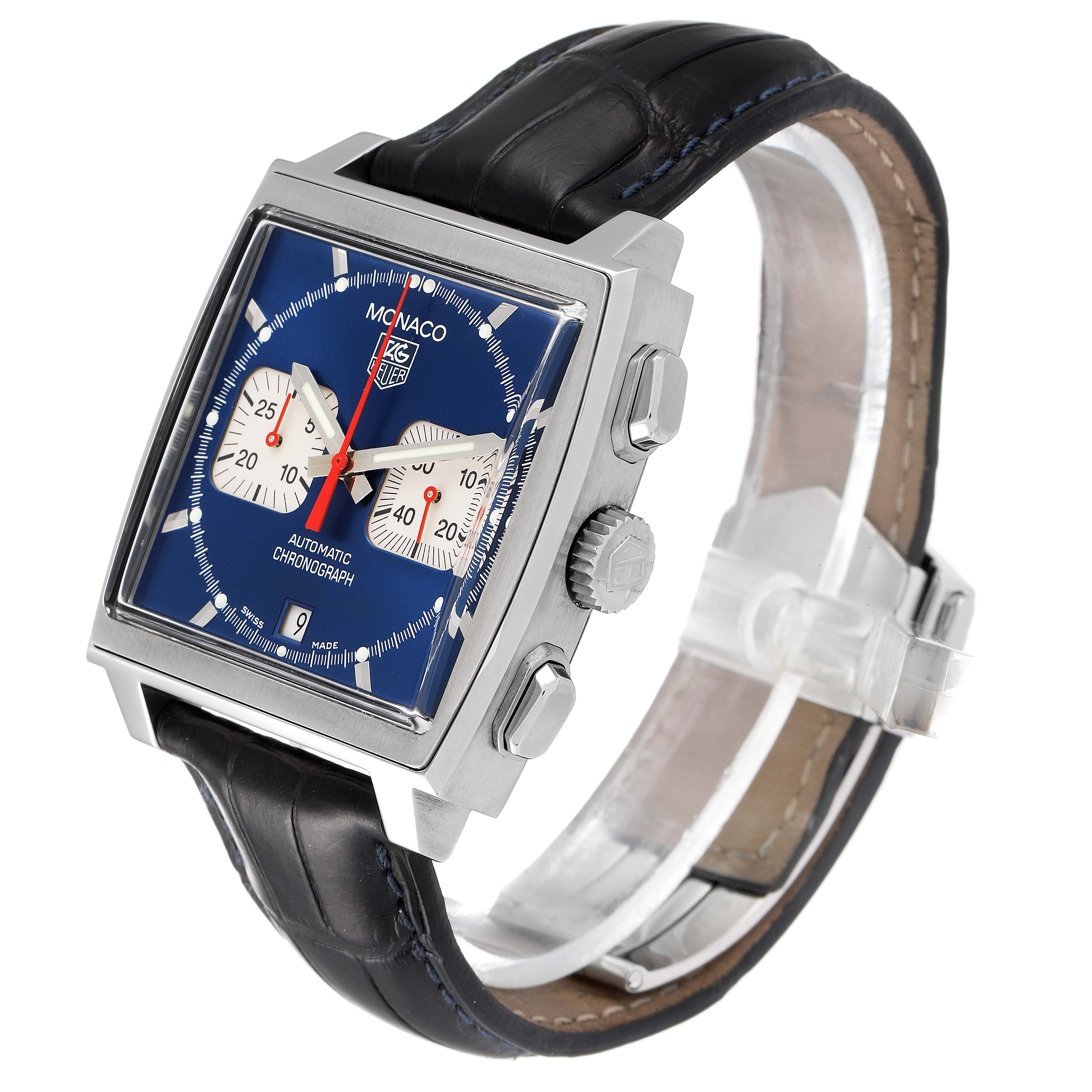 The Monaco model by Tag Heuer is shown at a three-quarter angle, displaying its face, crown, pushers, and strap.