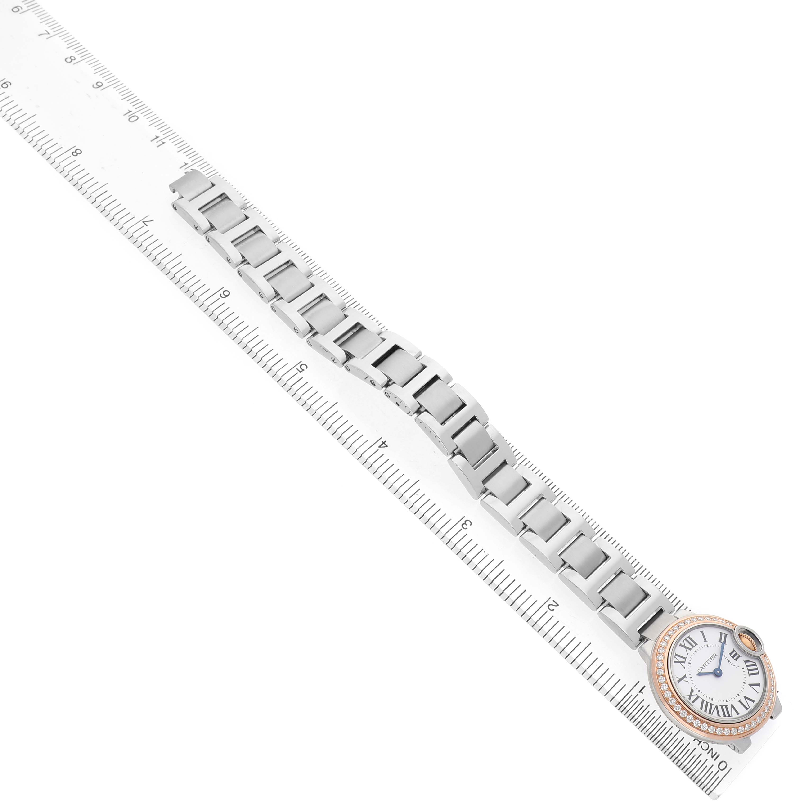 The Cartier Ballon Bleu WE902079 Women's Steel and Gold (two tone) Silver Dial watch is shown from a top-down angle, displaying its full bracelet and face alongside a ruler for scale.