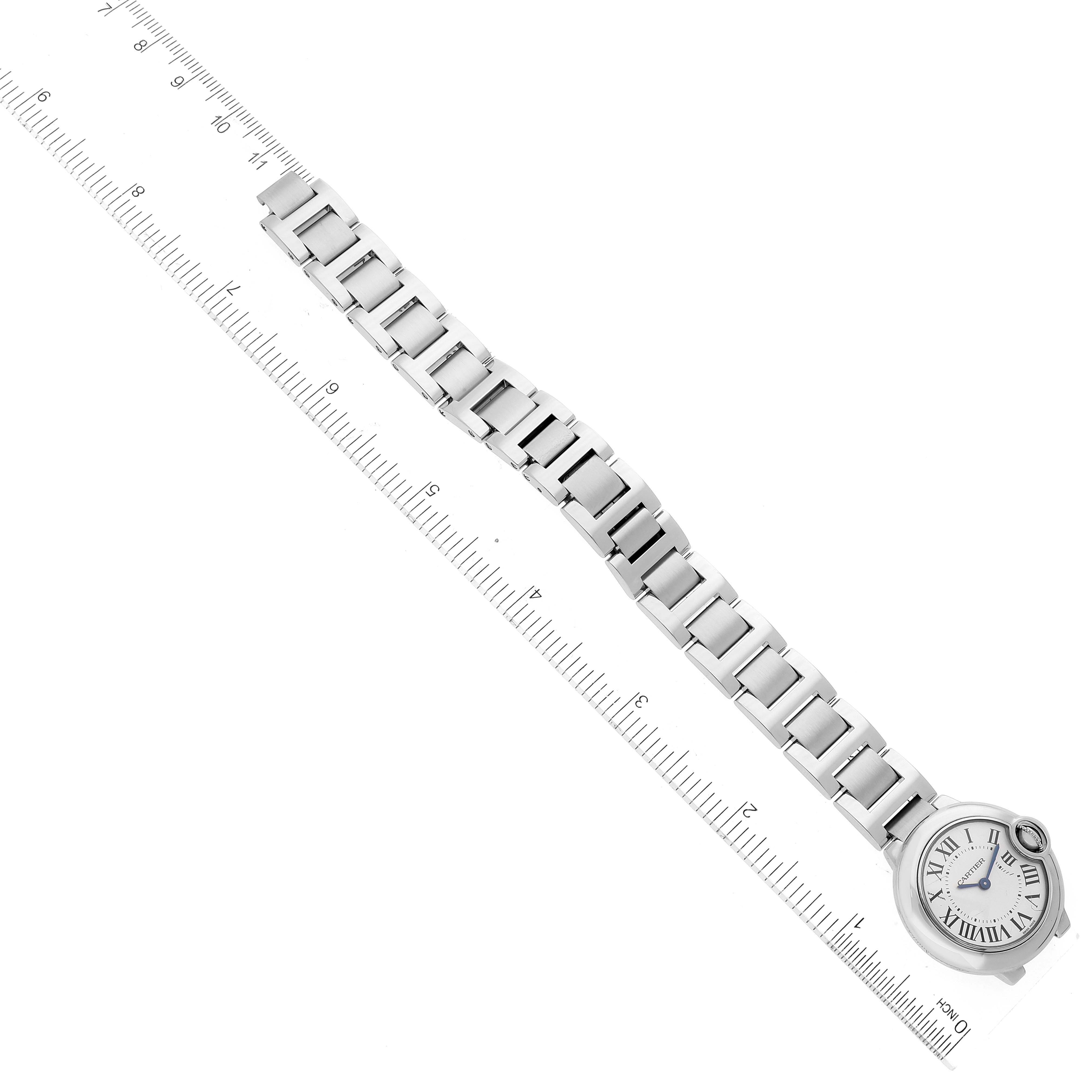 The image shows a top view of the Ballon Bleu de Cartier watch, displaying its face and full metal bracelet next to a ruler.