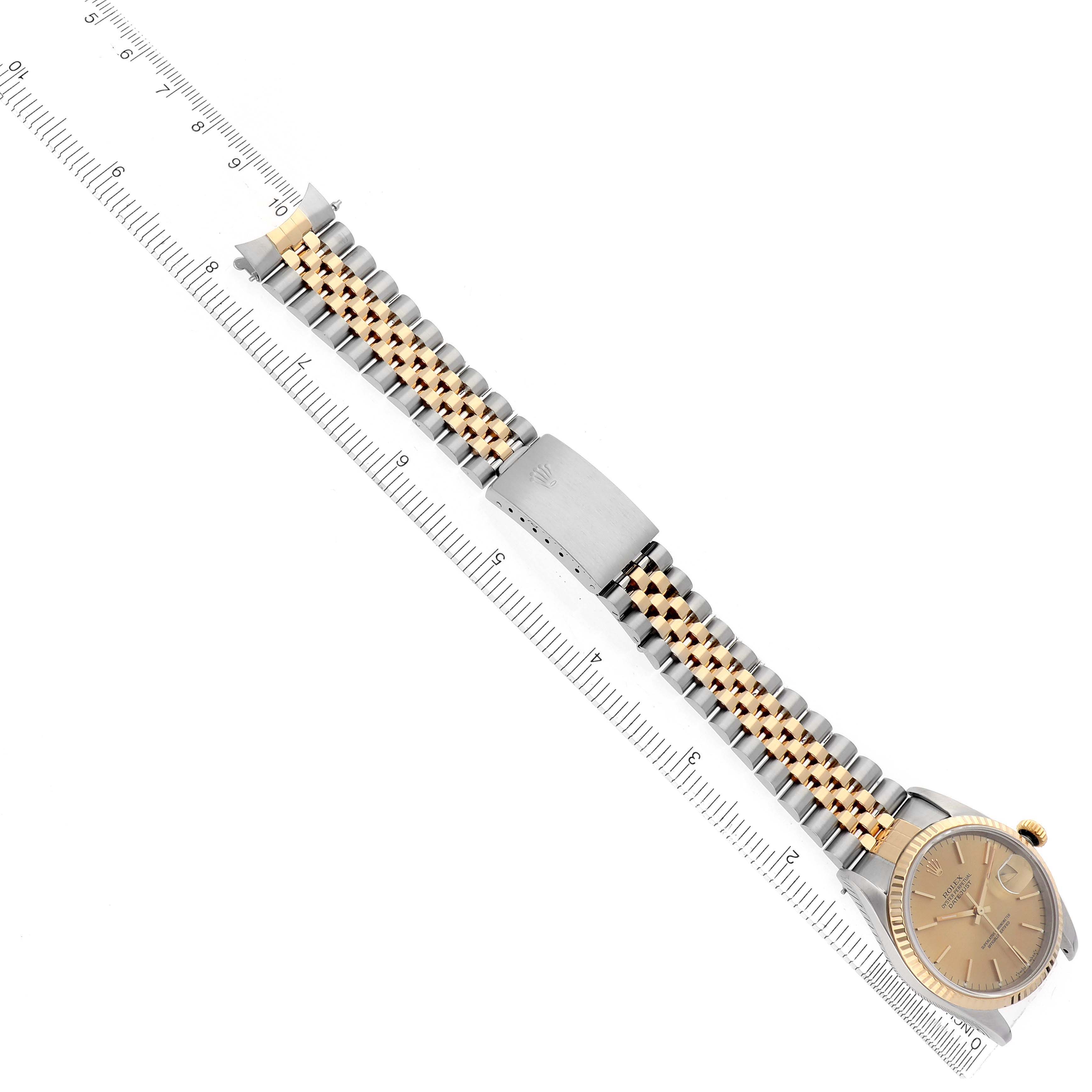 The image shows a Rolex Datejust 16233 Men
s Steel and Gold (two tone) Champagne Dial watch laid flat with its bracelet extended, alongside a ruler for scale.