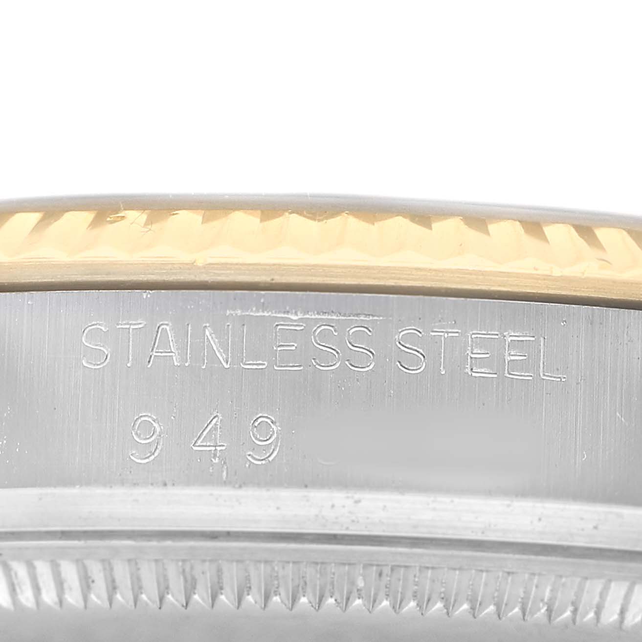 The image shows a close-up of the edge of a Rolex Datejust 16013 Men's Steel and Gold (two tone) Champagne Dial watch bezel with a "Stainless Steel" engraving.